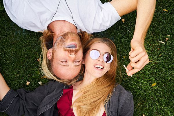 two people laying on grass smoking a joint