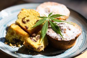 Muffins with raisins, topped with powdered sugar, and a cannabis leaf on a blue plate.