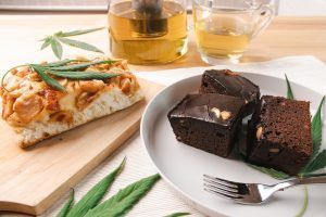 Cannabis-infused baked goods: bread, brownies, and tea, with marijuana leaves for decoration.