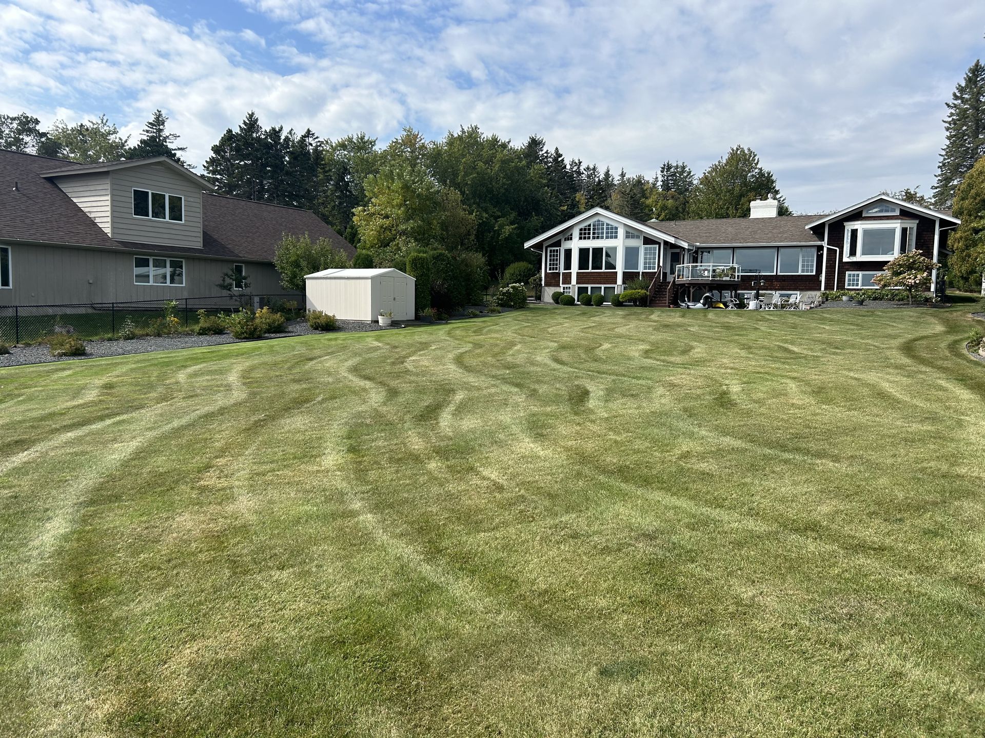 A large house is sitting on top of a lush green field.