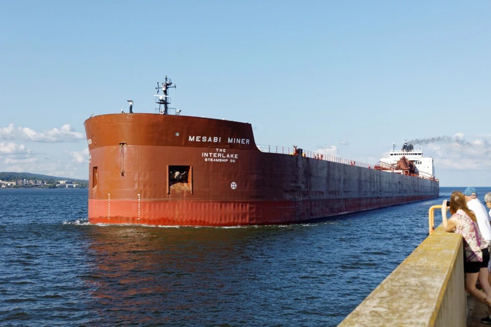 A large red ship is floating on top of a body of water.