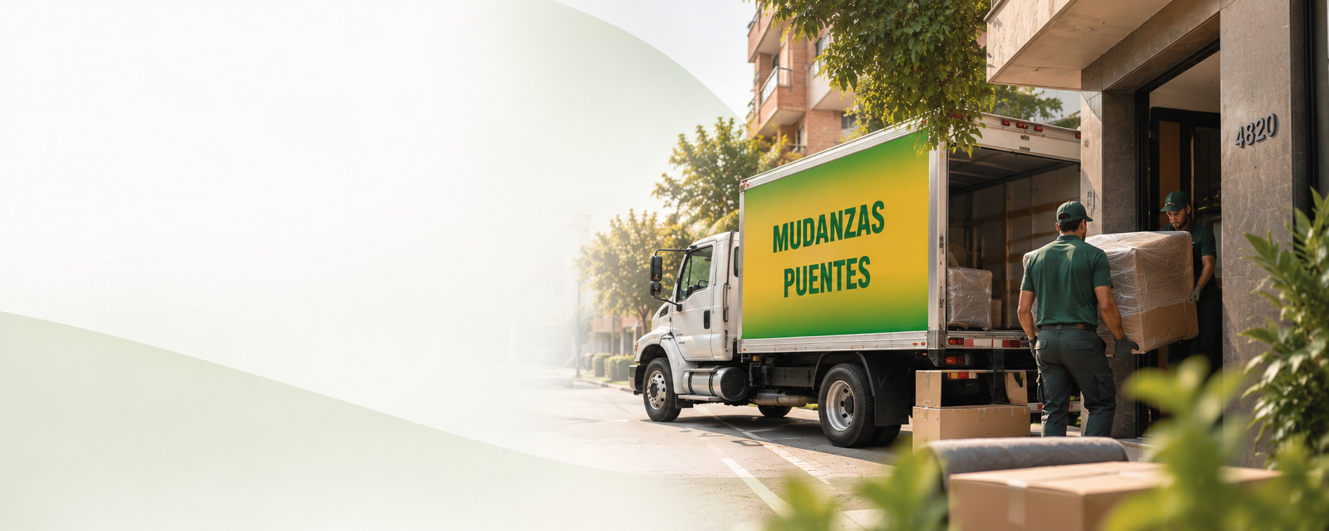 Un camión de reparto estacionado frente a un edificio con dos trabajadores cargando cajas desde la parte trasera.