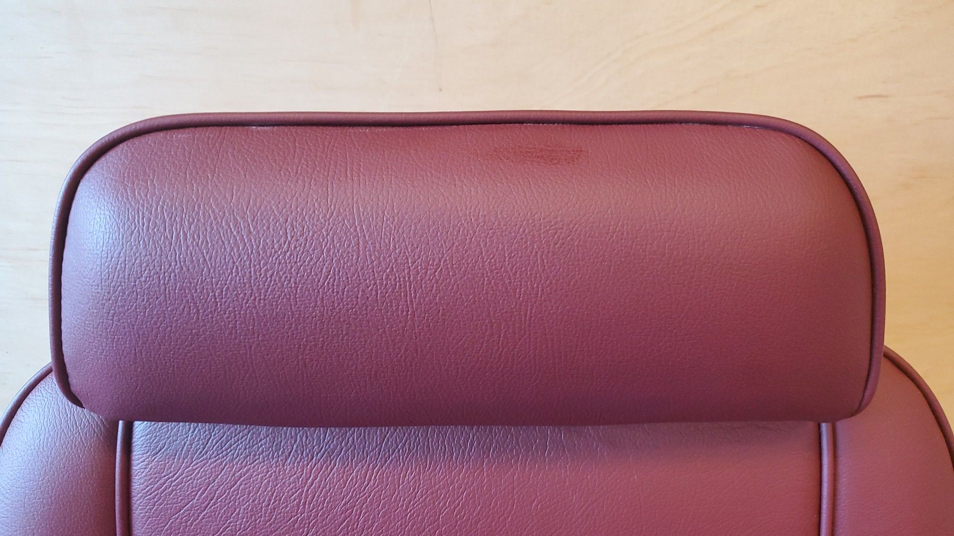 Close-up of a burgundy leather chair backrest with rounded corners and visible stitching