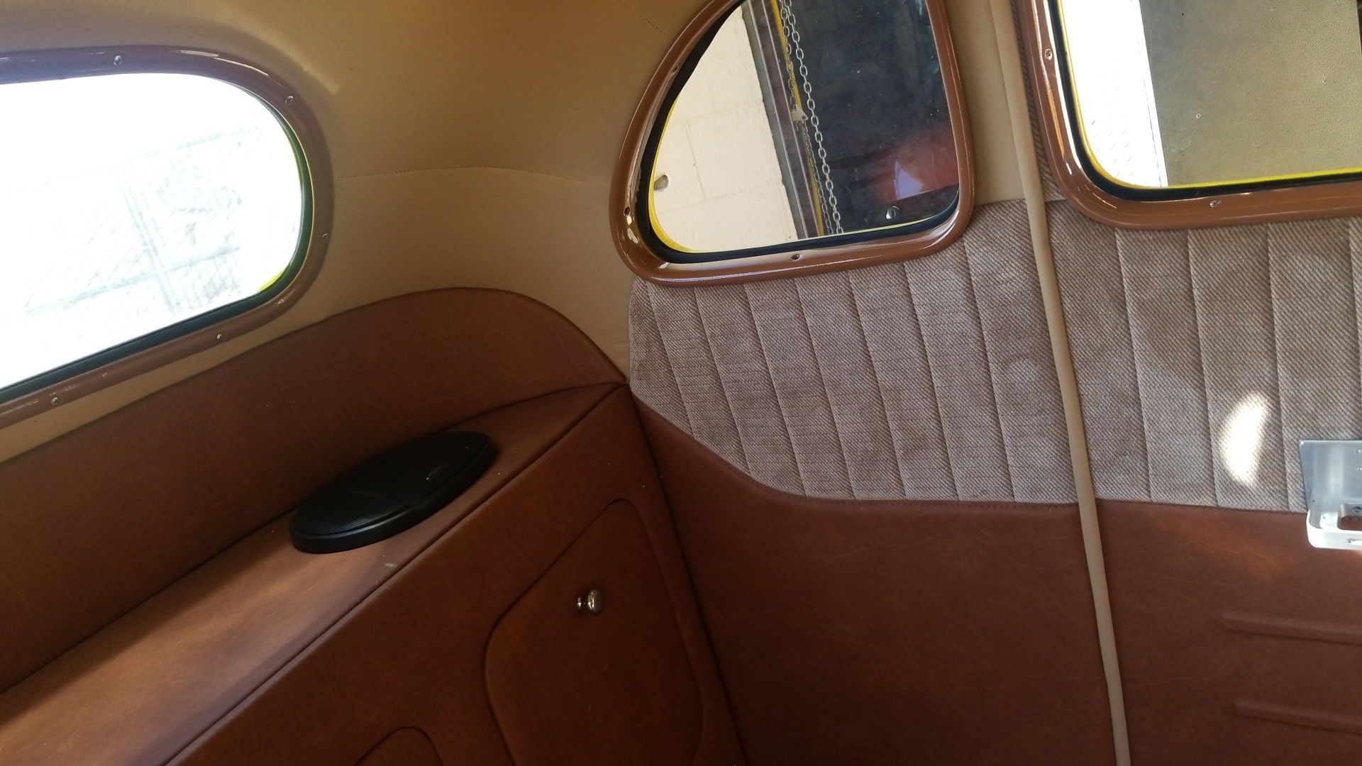 Vintage airplane cabin interior with tan paneling, rounded windows, and wood trim
