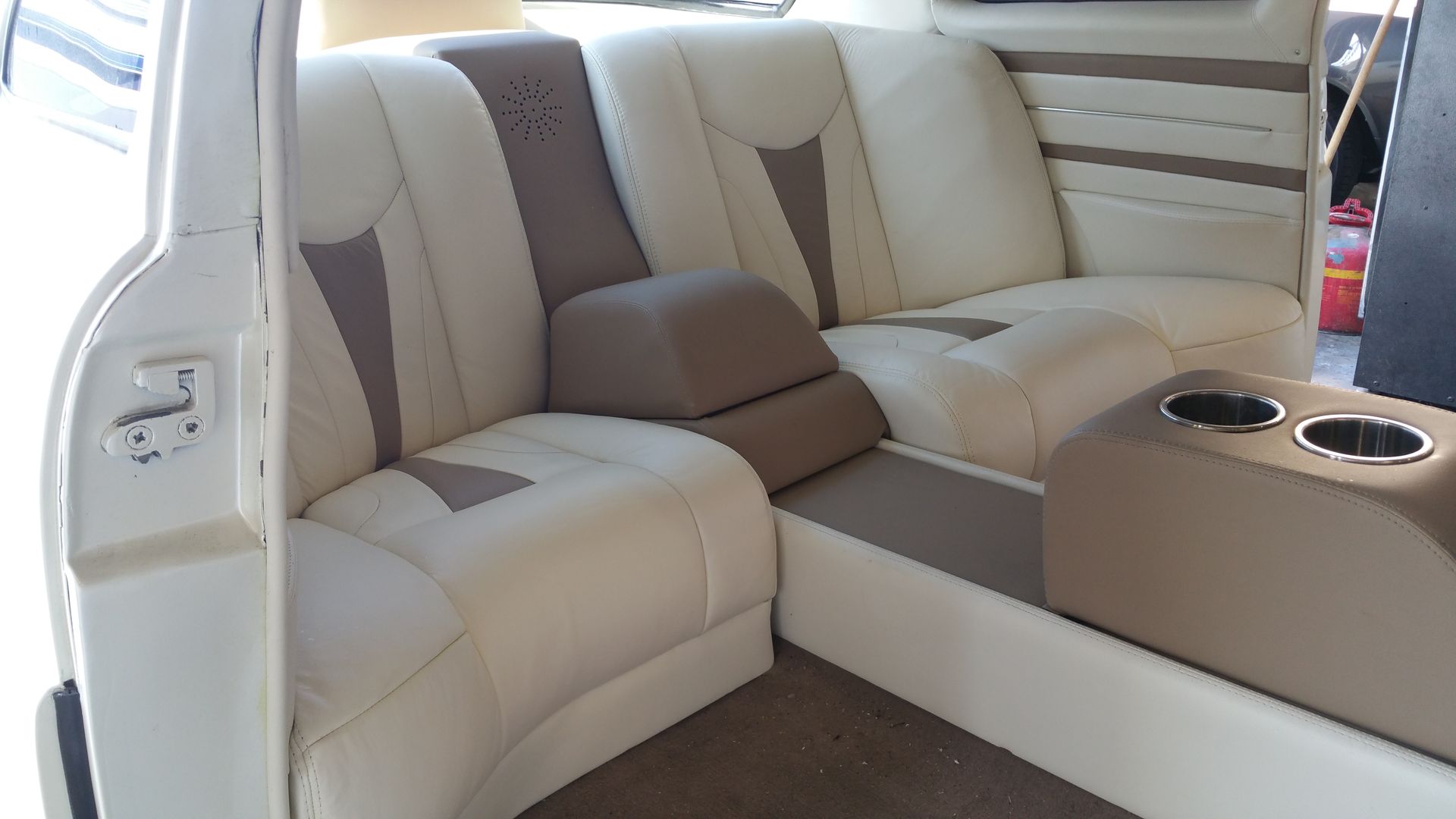 Beige and brown boat cabin seating with cushioned bench and cup holders