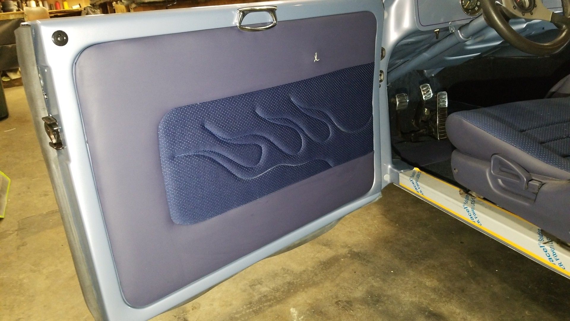 Close-up of an open suitcase with a gray panel and dark blue insert, showing a seatback or interior lining