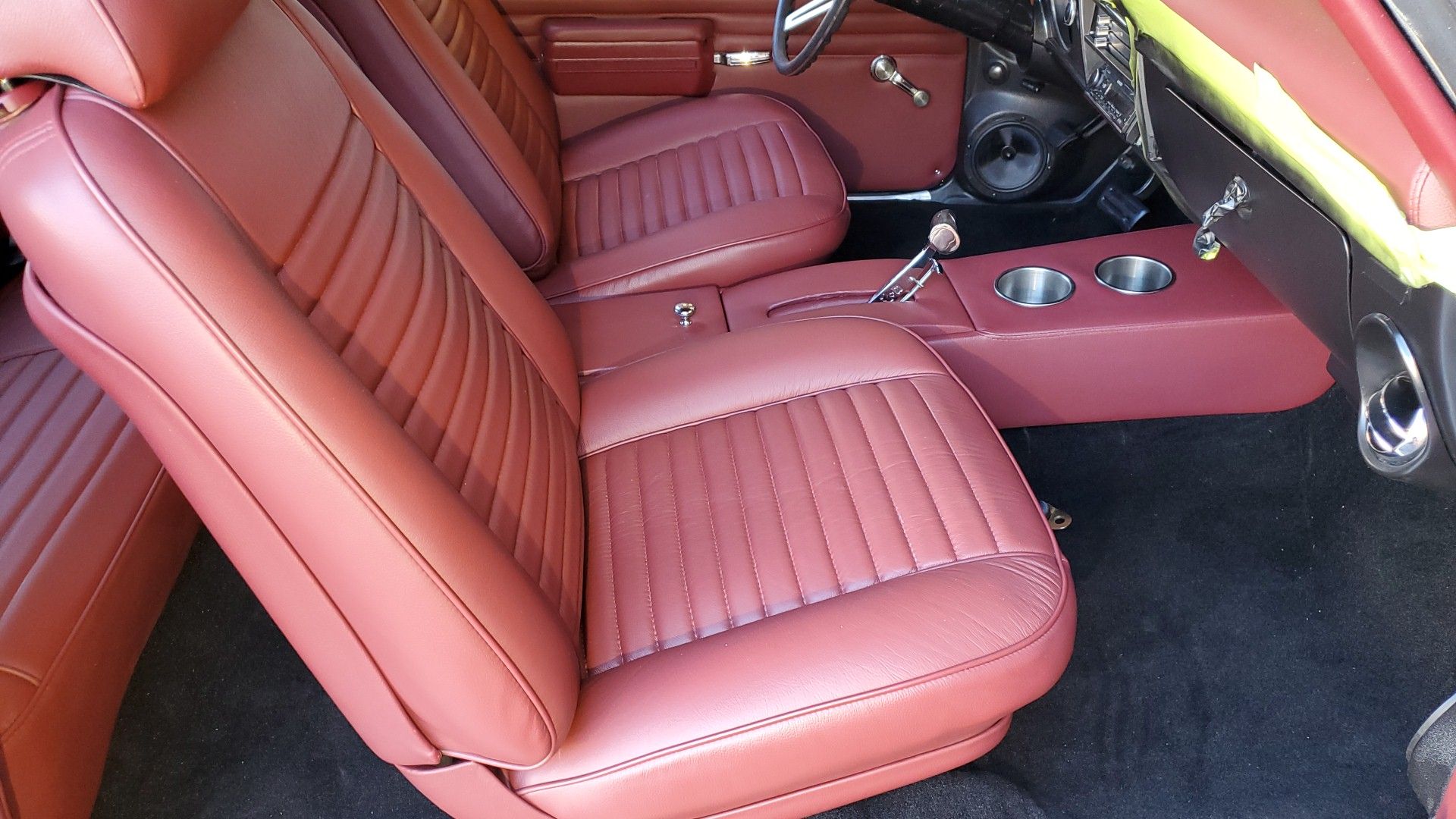 Red leather car interior with front seats, center console, and black floor mats