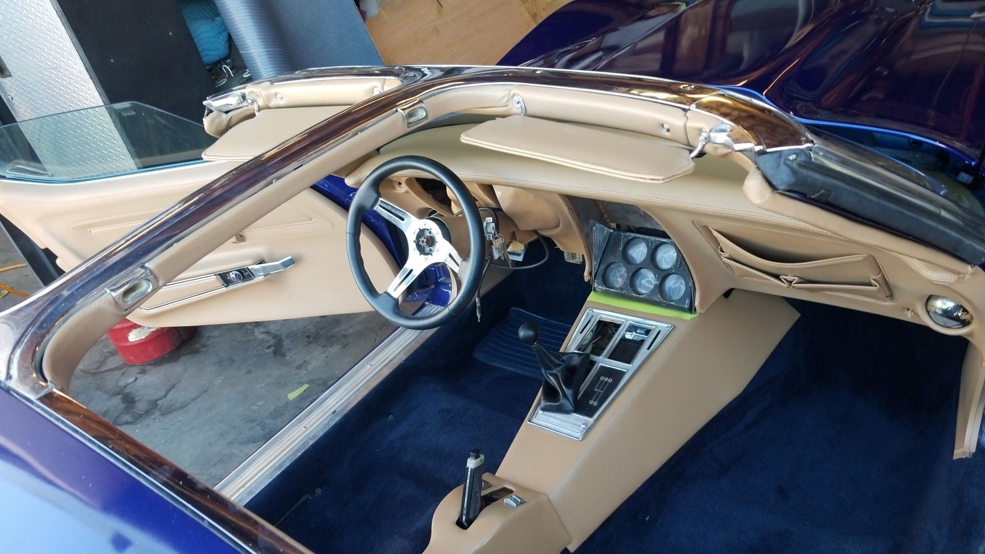 Blue luxury car cockpit with tan interior, chrome steering wheel, and central dashboard gauges