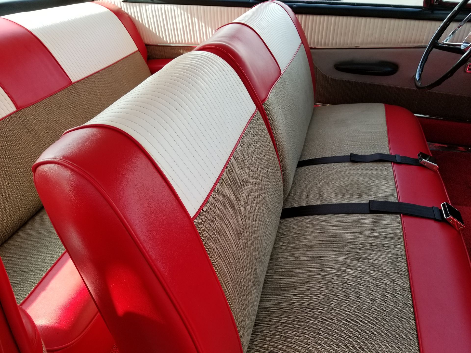 Vintage car back seat with red and white upholstery and seat belts