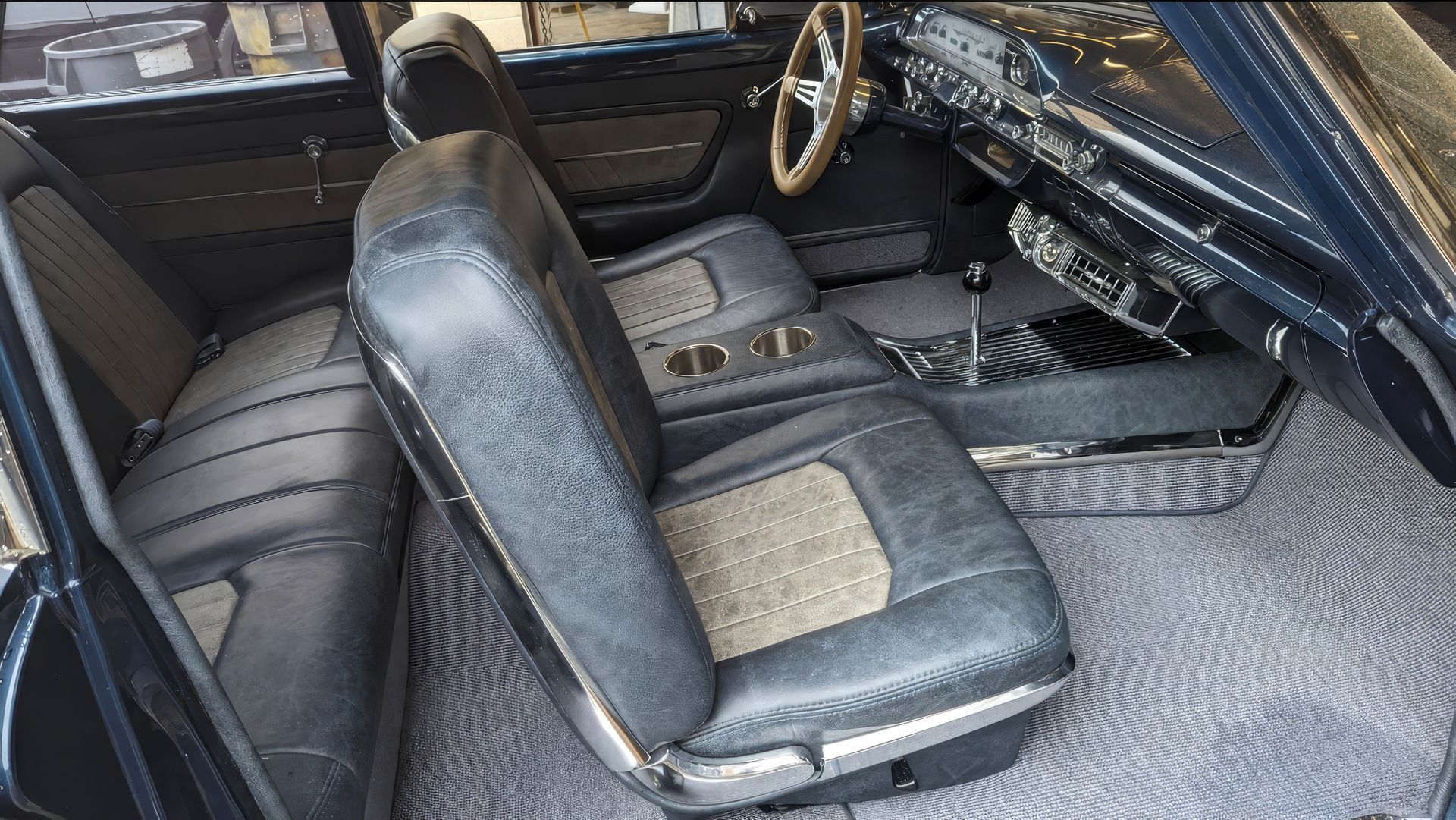 Interior of a classic car with black leather seats and dashboard, viewed from the passenger side