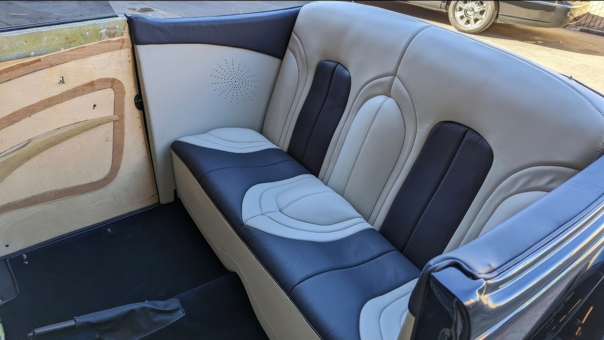 Gray-and-white upholstered boat bench seating with black floor flooring and wooden side paneling