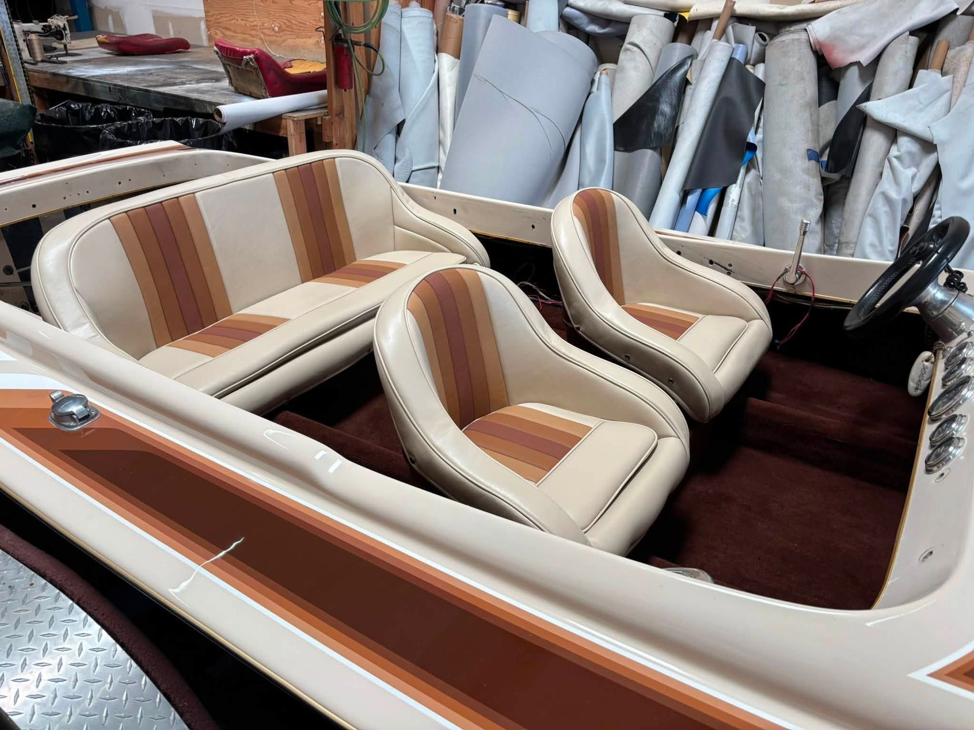 Small white-and-brown striped boat interior with two cushioned seats and a matching side panel