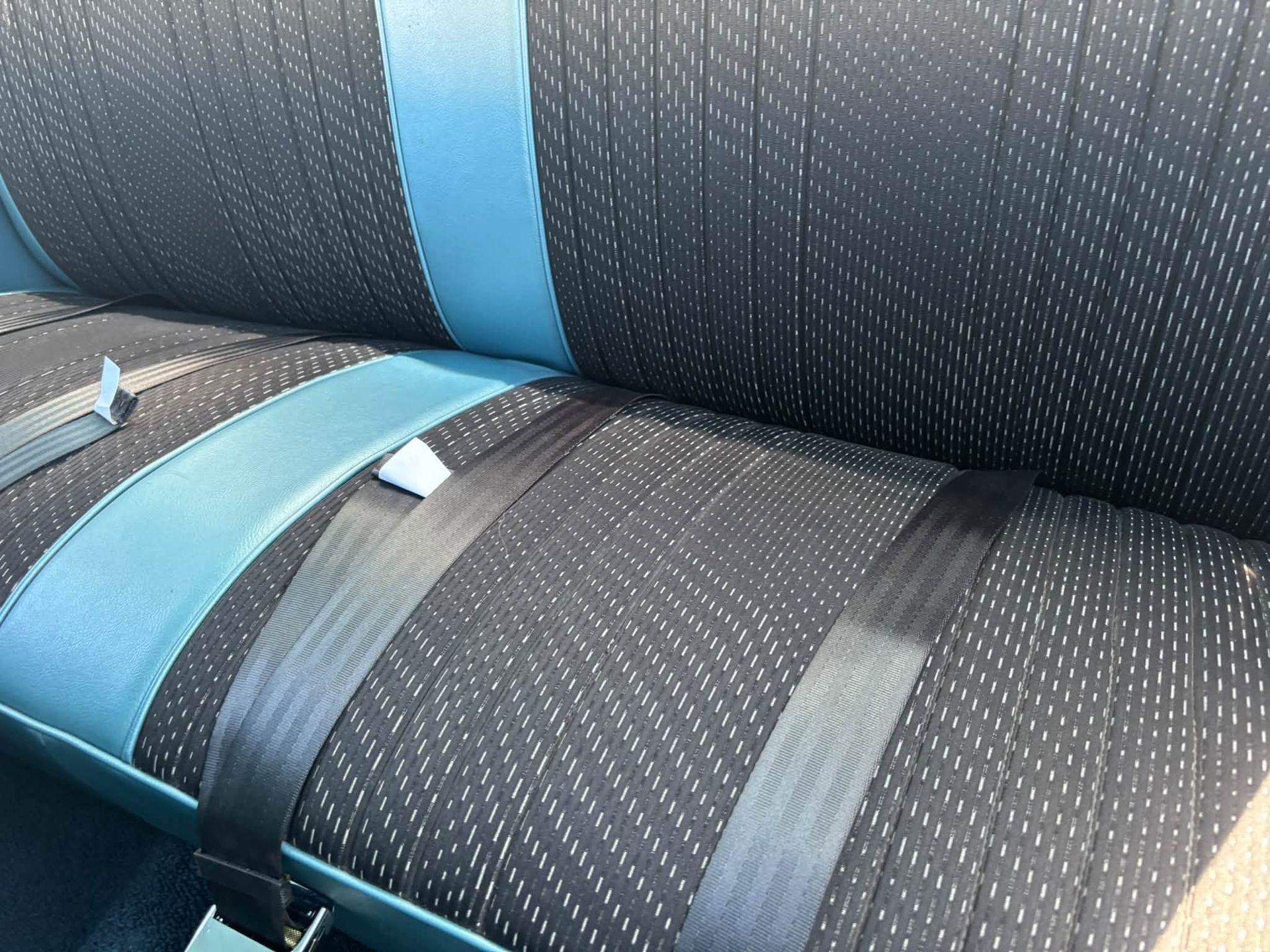 Close-up of a dark fabric car seat with blue accents and seatbelt straps