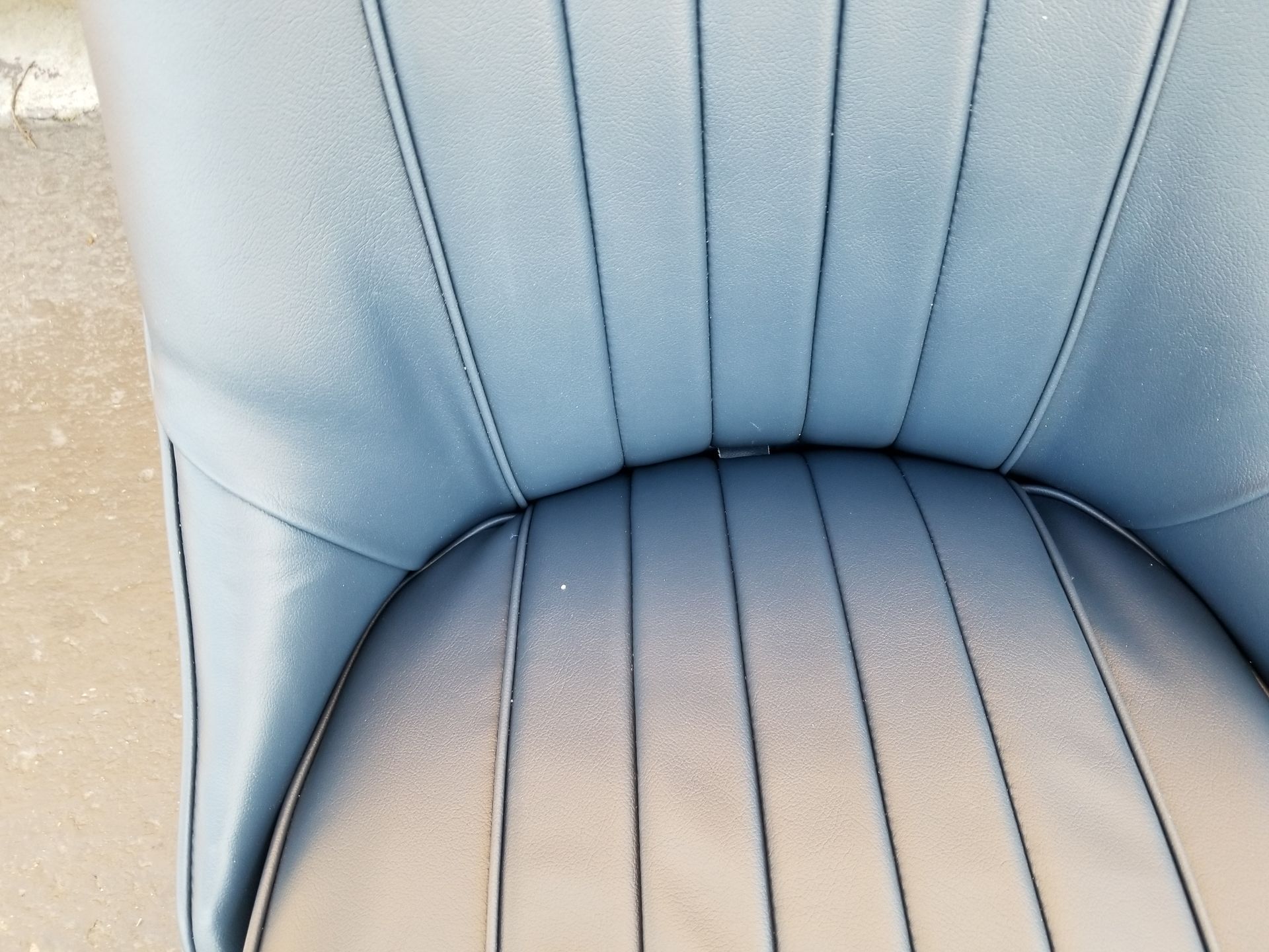 Close-up of a light blue upholstered chair seat and back with vertical stitched seams