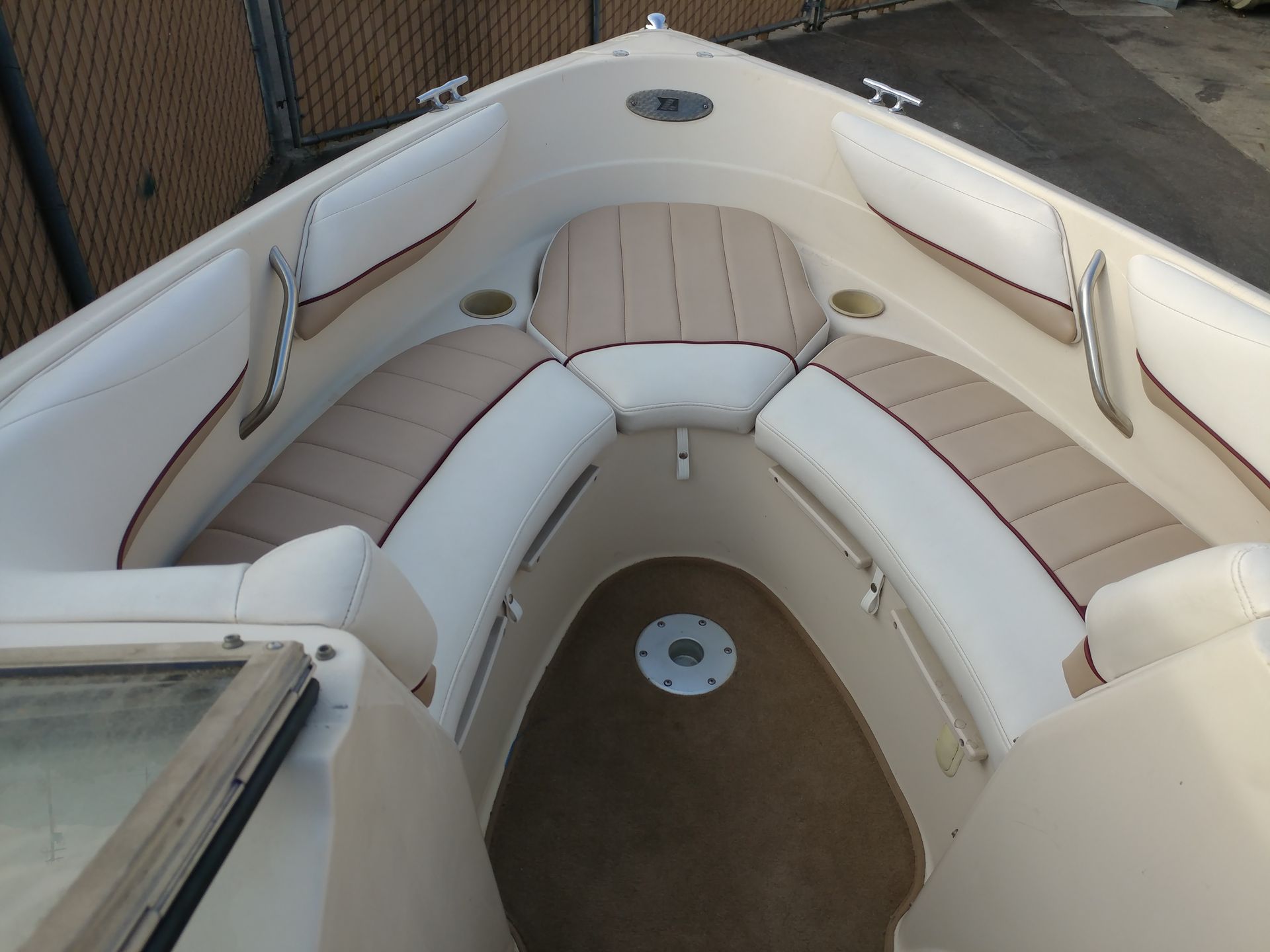 White cushioned boat seating around a small tan deck area, viewed from above.