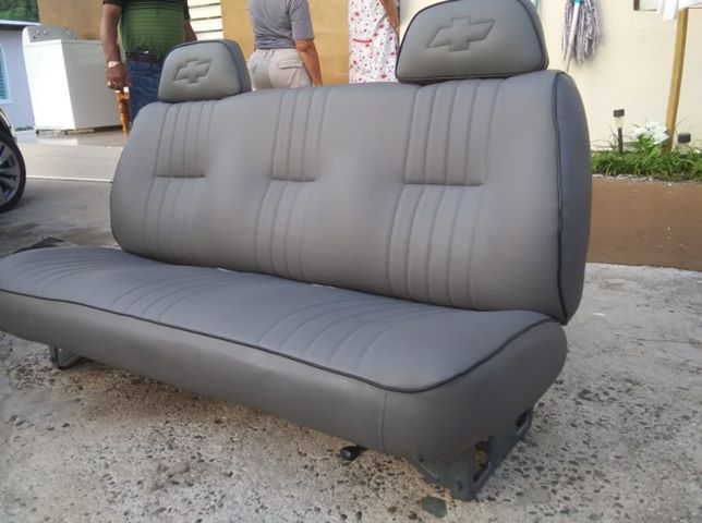 Gray automotive rear bench seat with headrests, shown outdoors on the ground