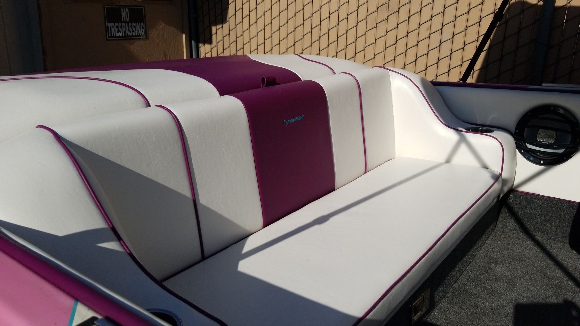 White and purple cushioned boat bench seat against a netted deck wall.