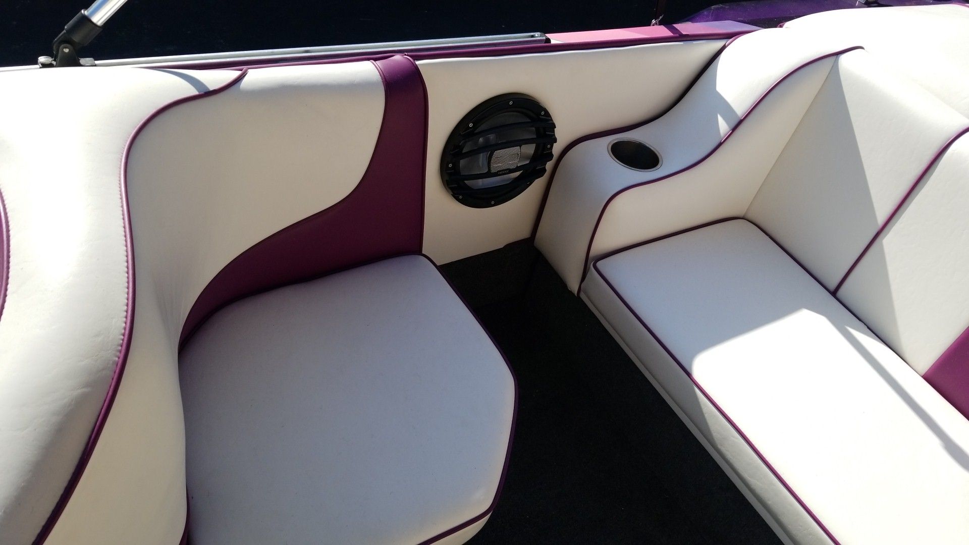 White and purple boat seating around a black circular speaker in a sunlit interior
