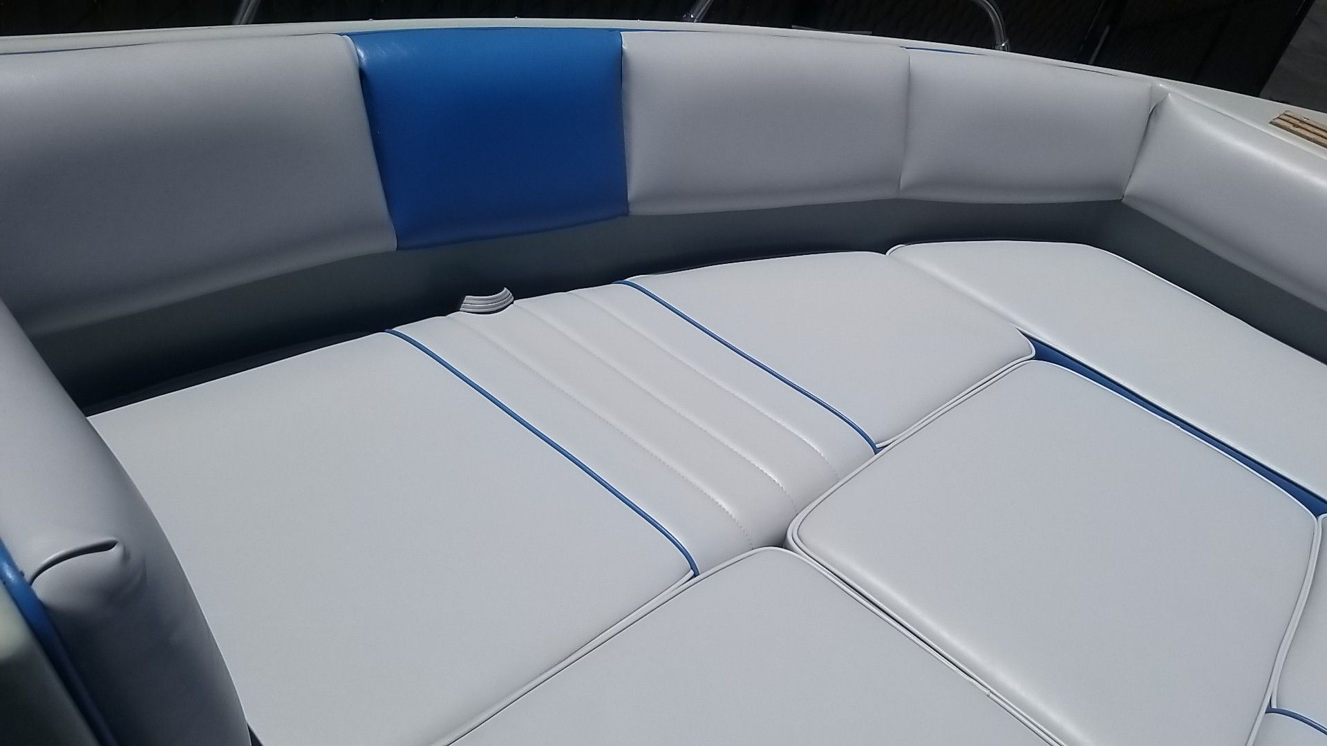 White and gray cushioned boat seating with blue accent panels and stitching.