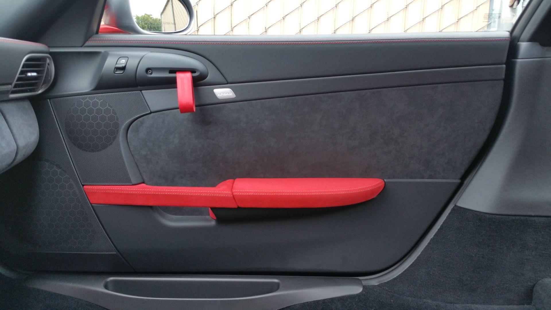 Red and black car door interior with armrest and handle