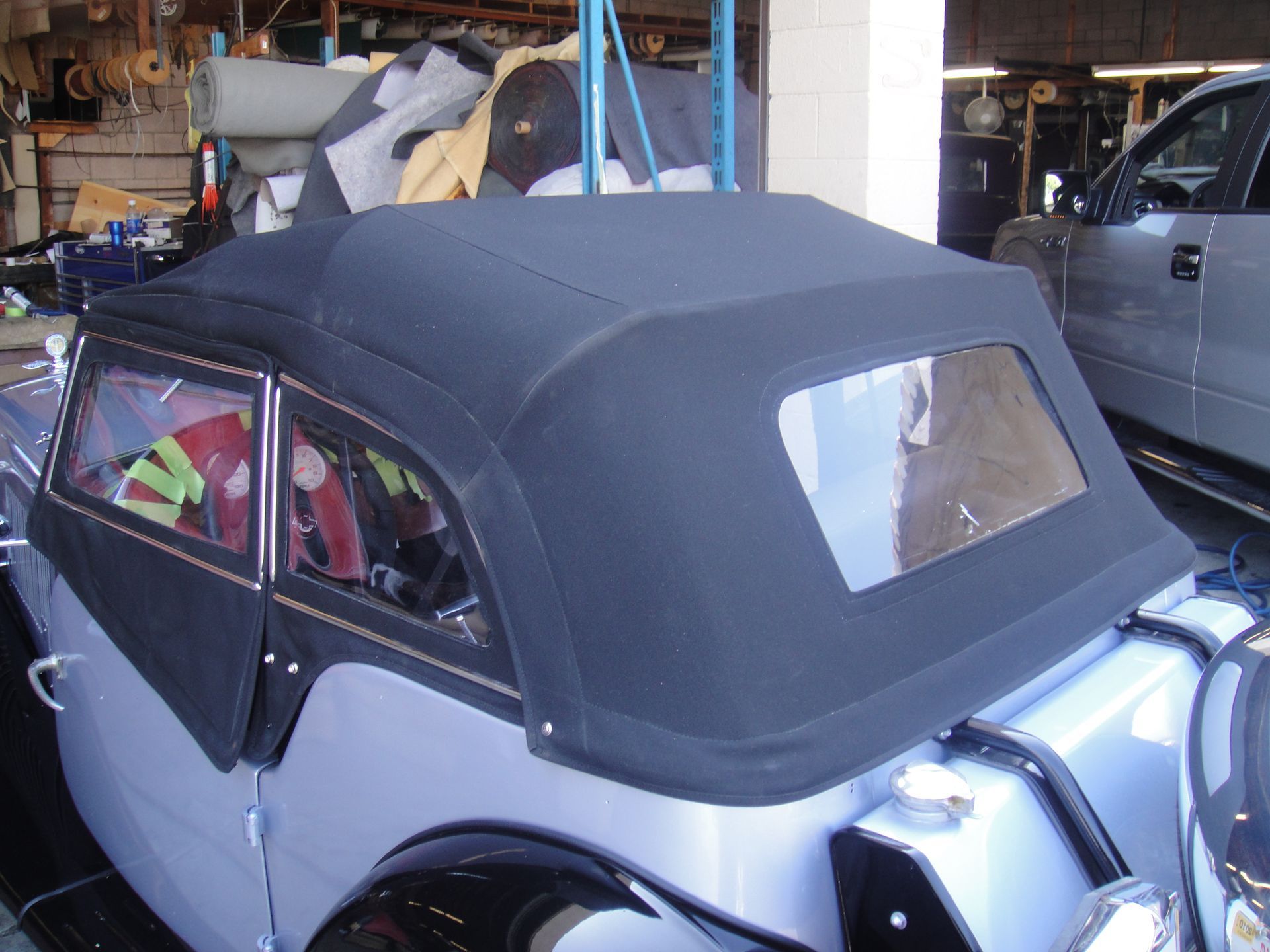 Vintage gray convertible with black soft top parked in a garage