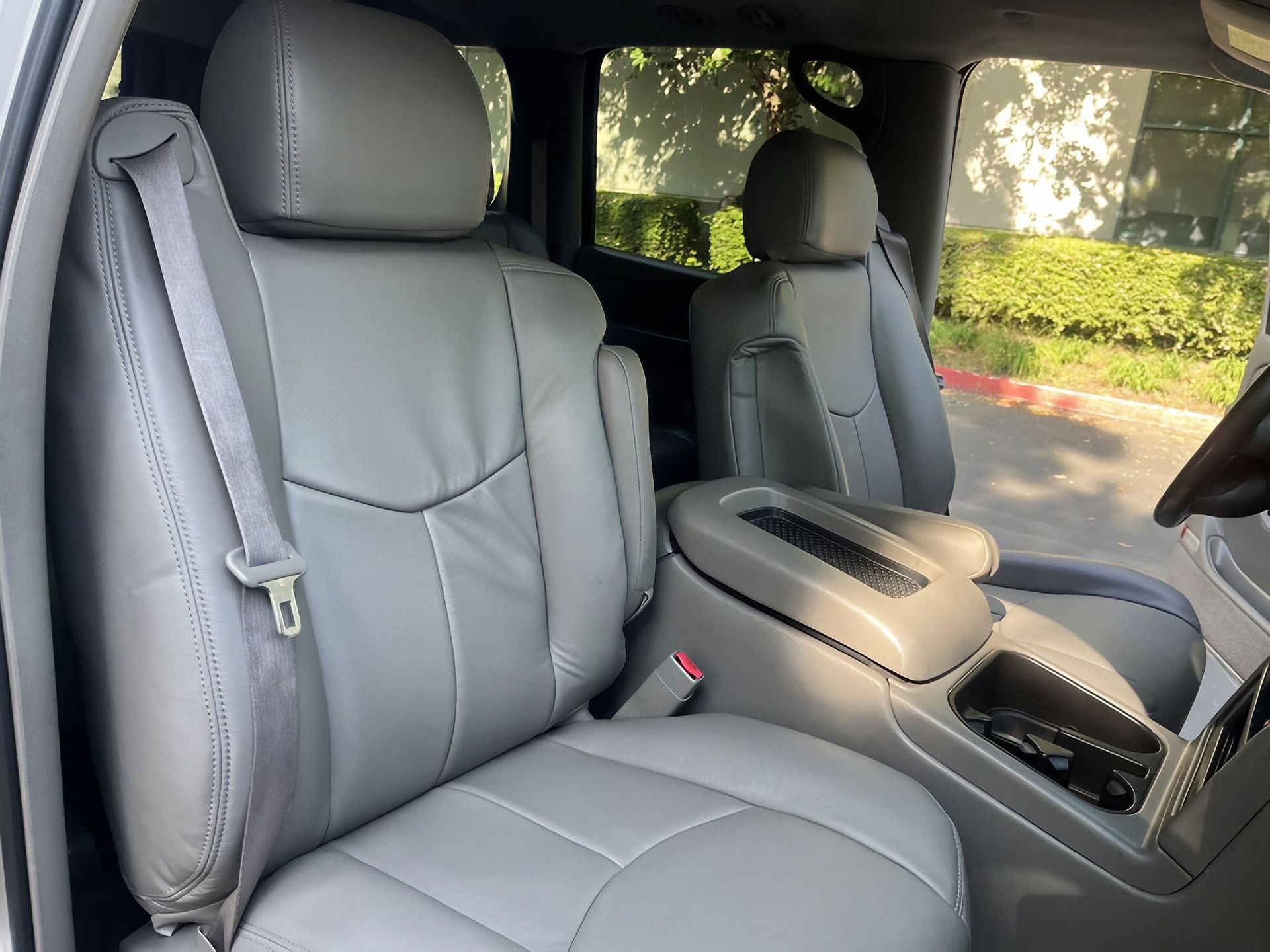 Gray leather SUV front seats with center console and cupholders, viewed from the passenger side