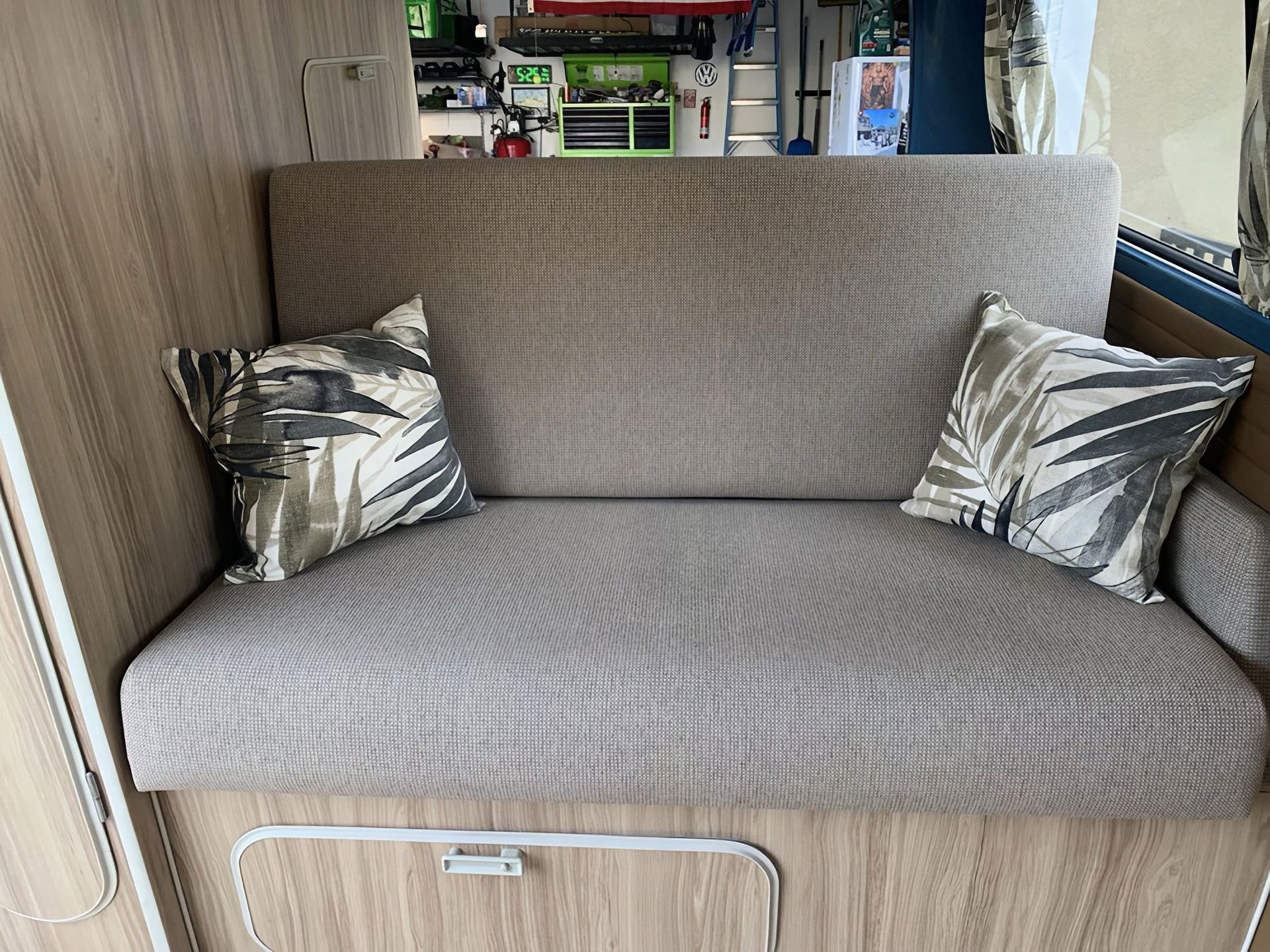 Beige patterned sofa with two metallic silver pillows in a narrow indoor space
