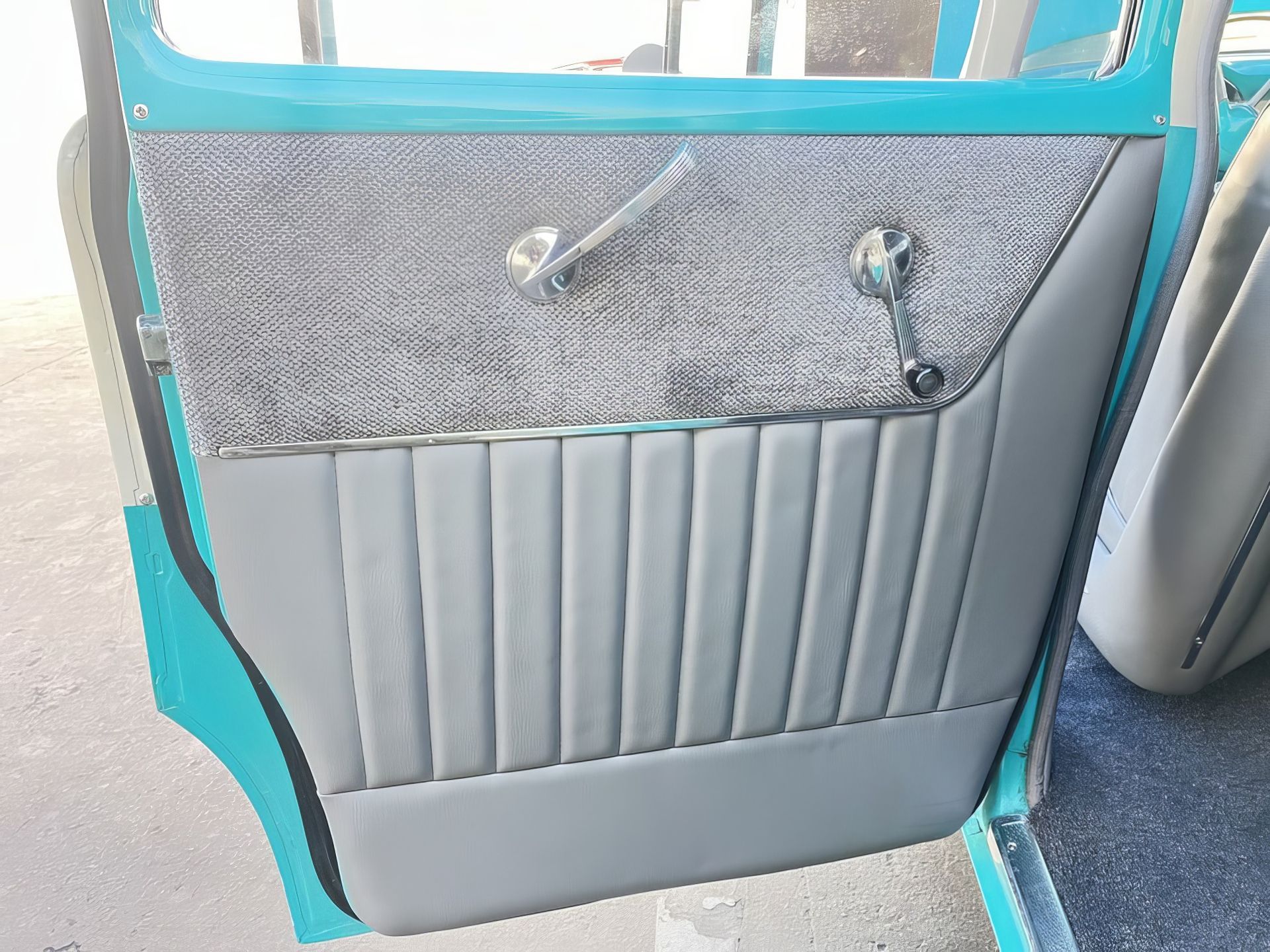 Interior car door panel in gray and turquoise with a patterned upper section and vertical pleats below