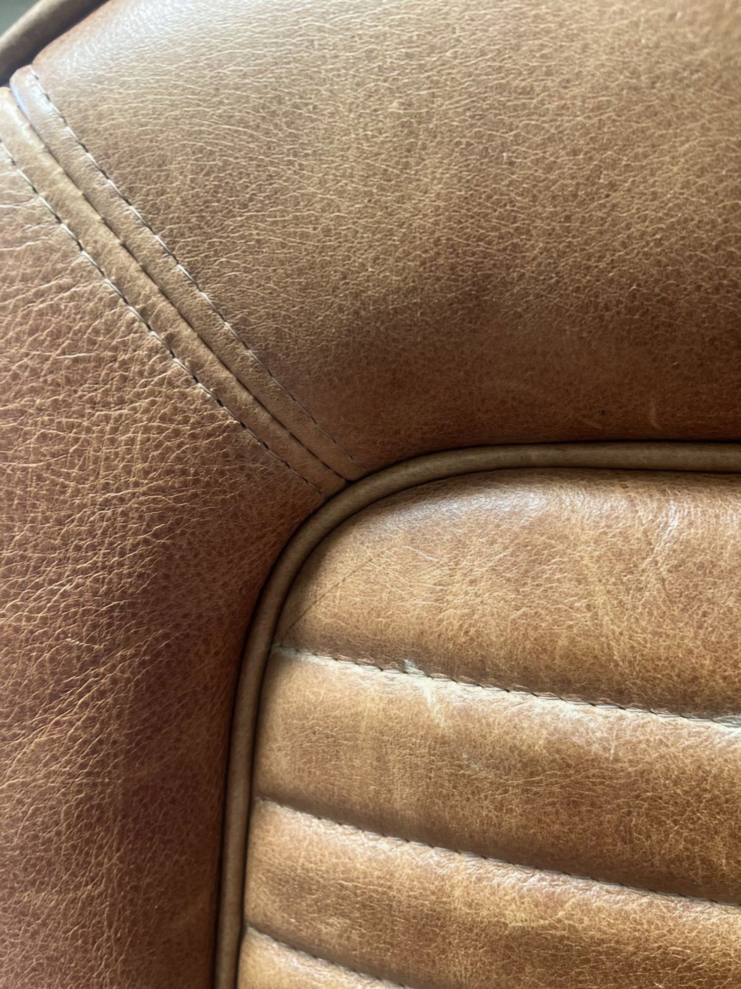 Close-up of brown leather upholstery with visible stitching and curved seam.