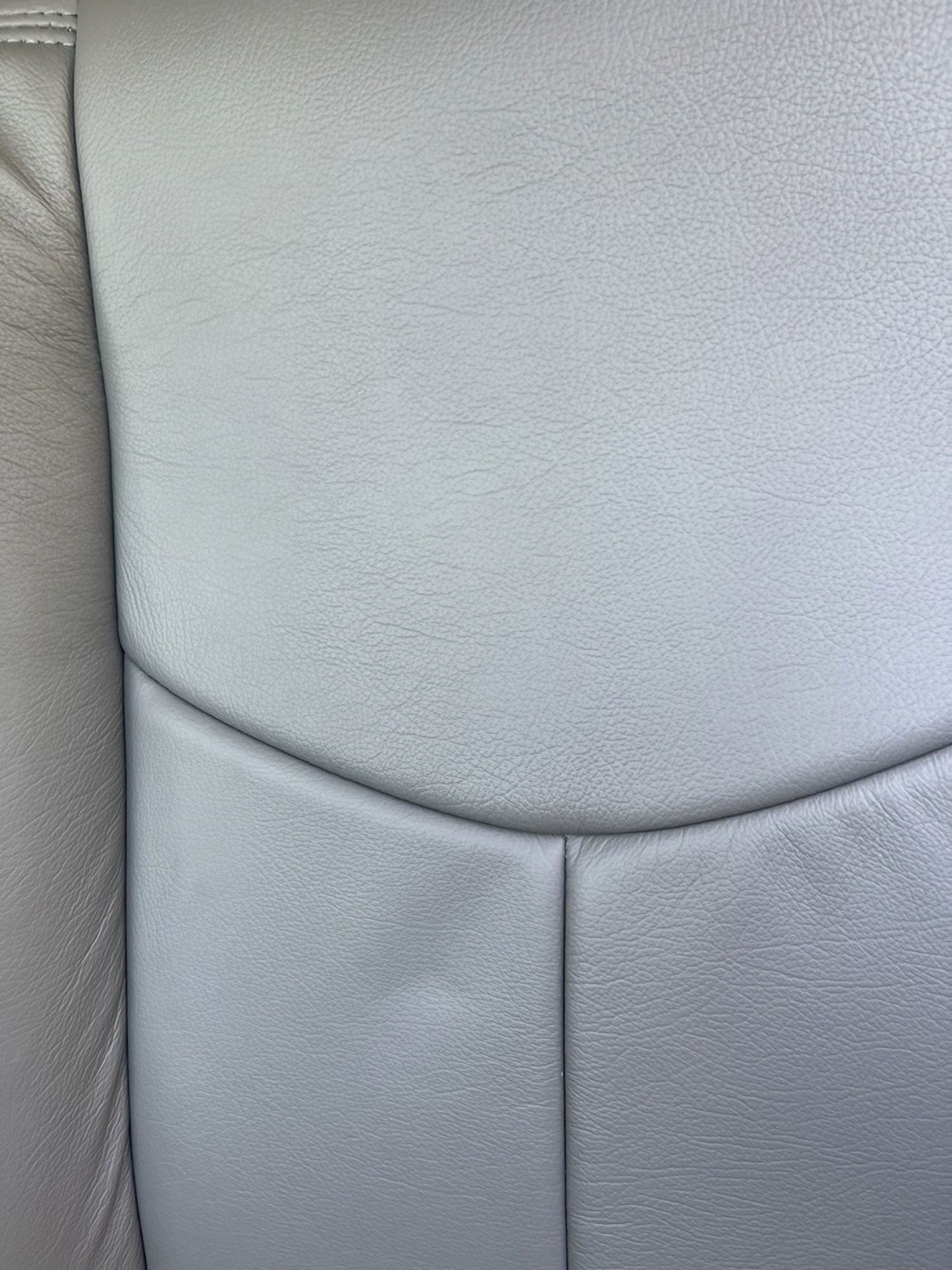 Close-up of light gray upholstered seat with curved seams and textured fabric.