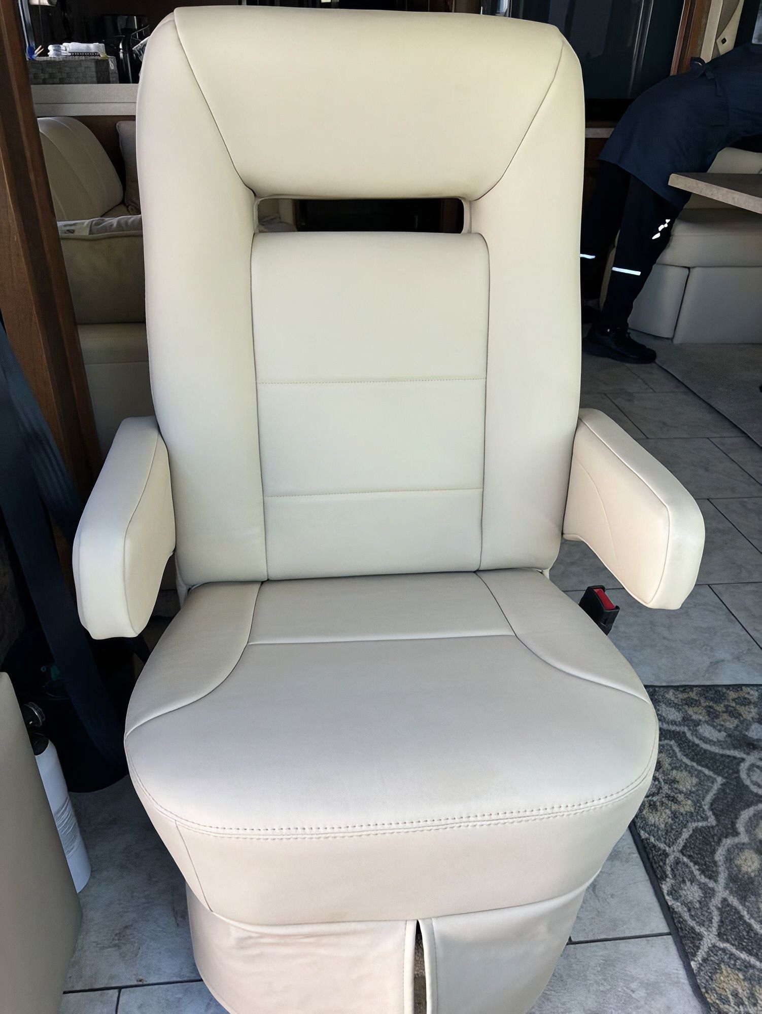 Cream-colored upholstered armchair with arms and high back in a room.