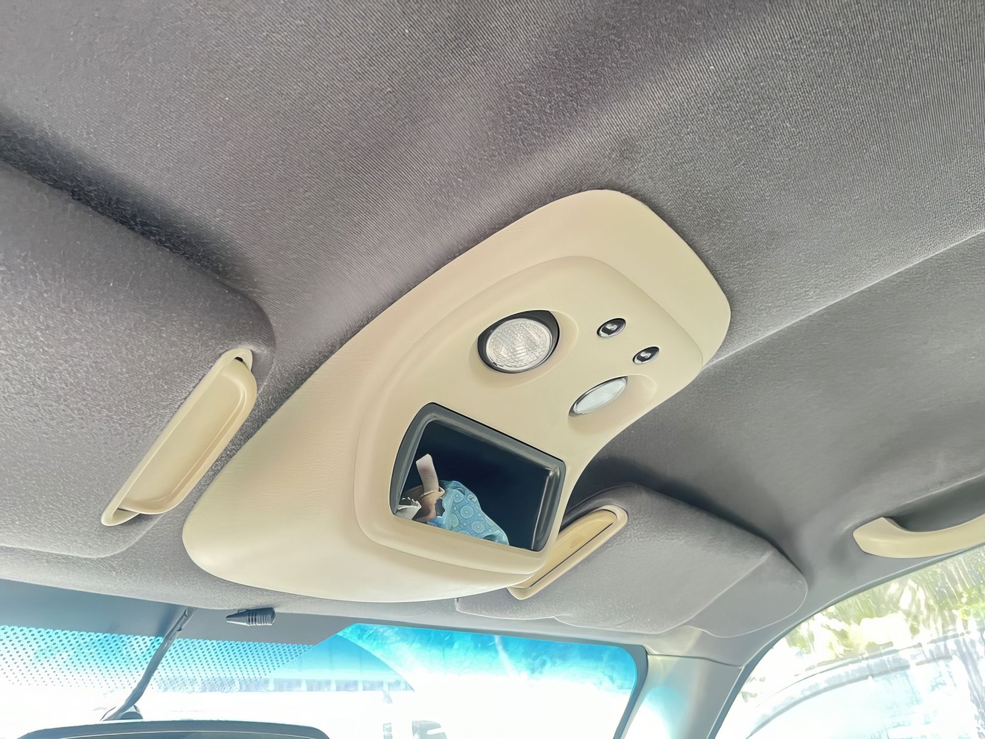 Car ceiling with overhead console, lights, sunglasses holder, and rearview mirror visible