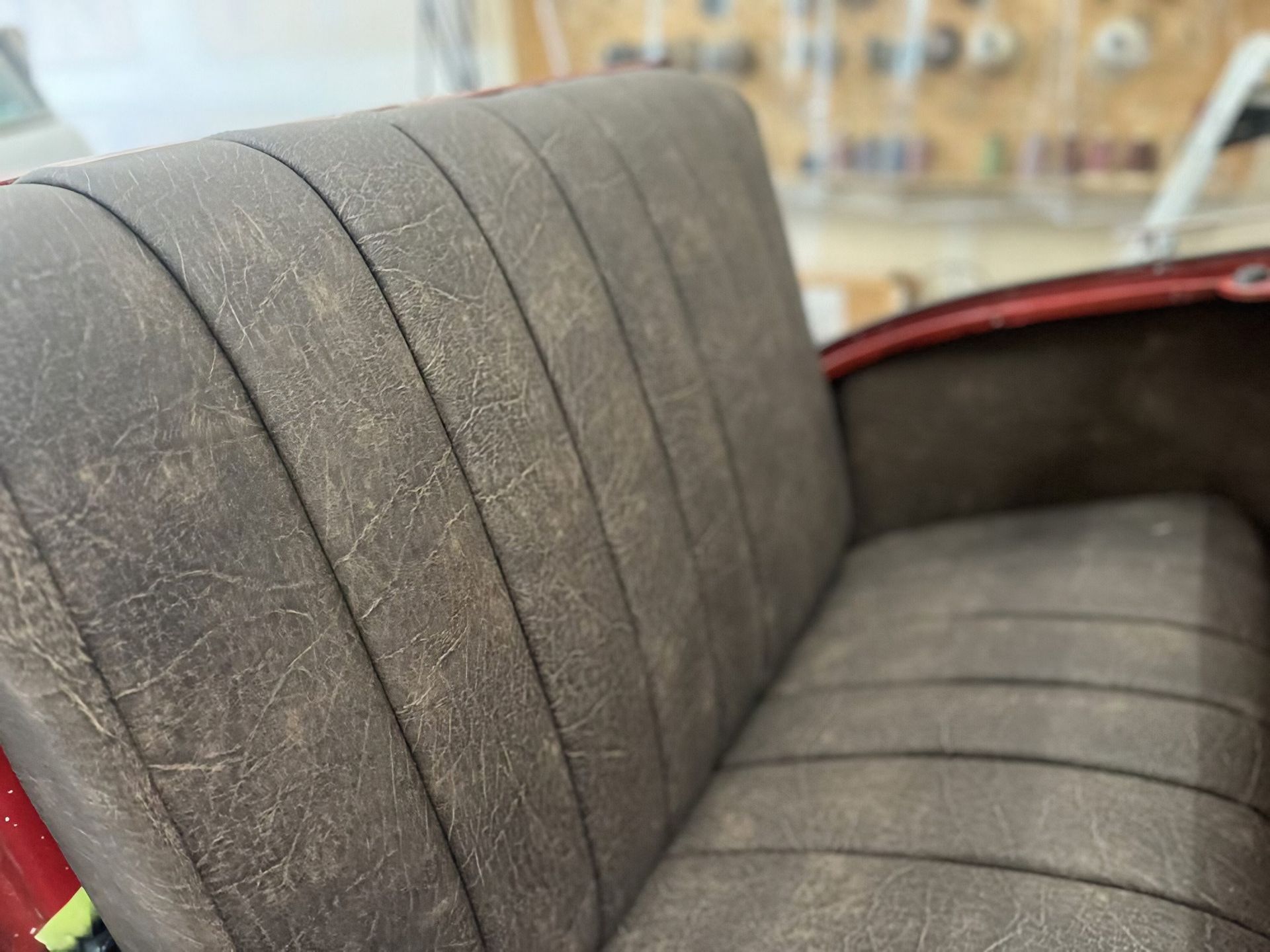 Gray upholstered bench seat with red trim in a softly lit indoor setting