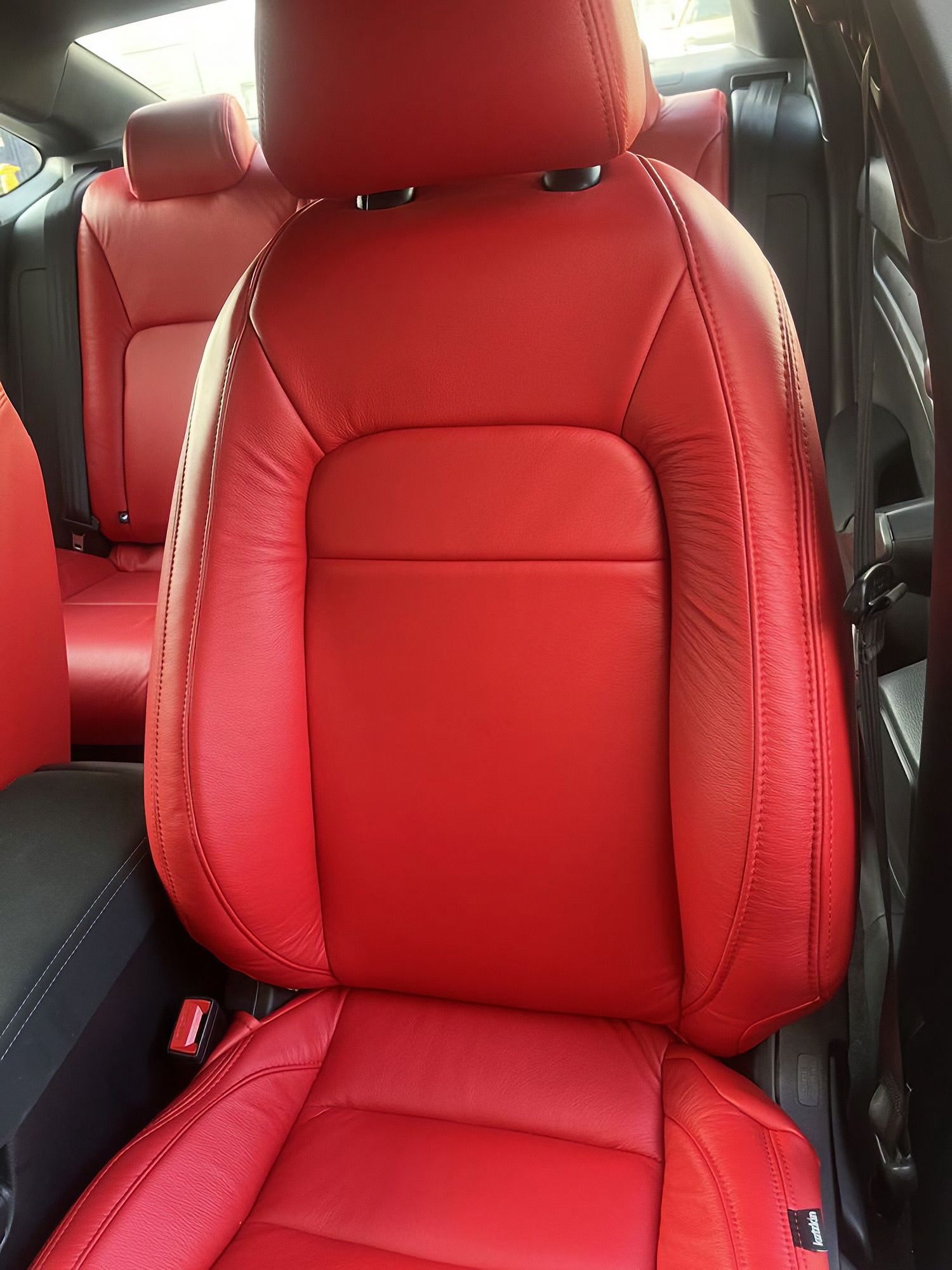 Red car seat with black trim in a vehicle interior, shown close up.
