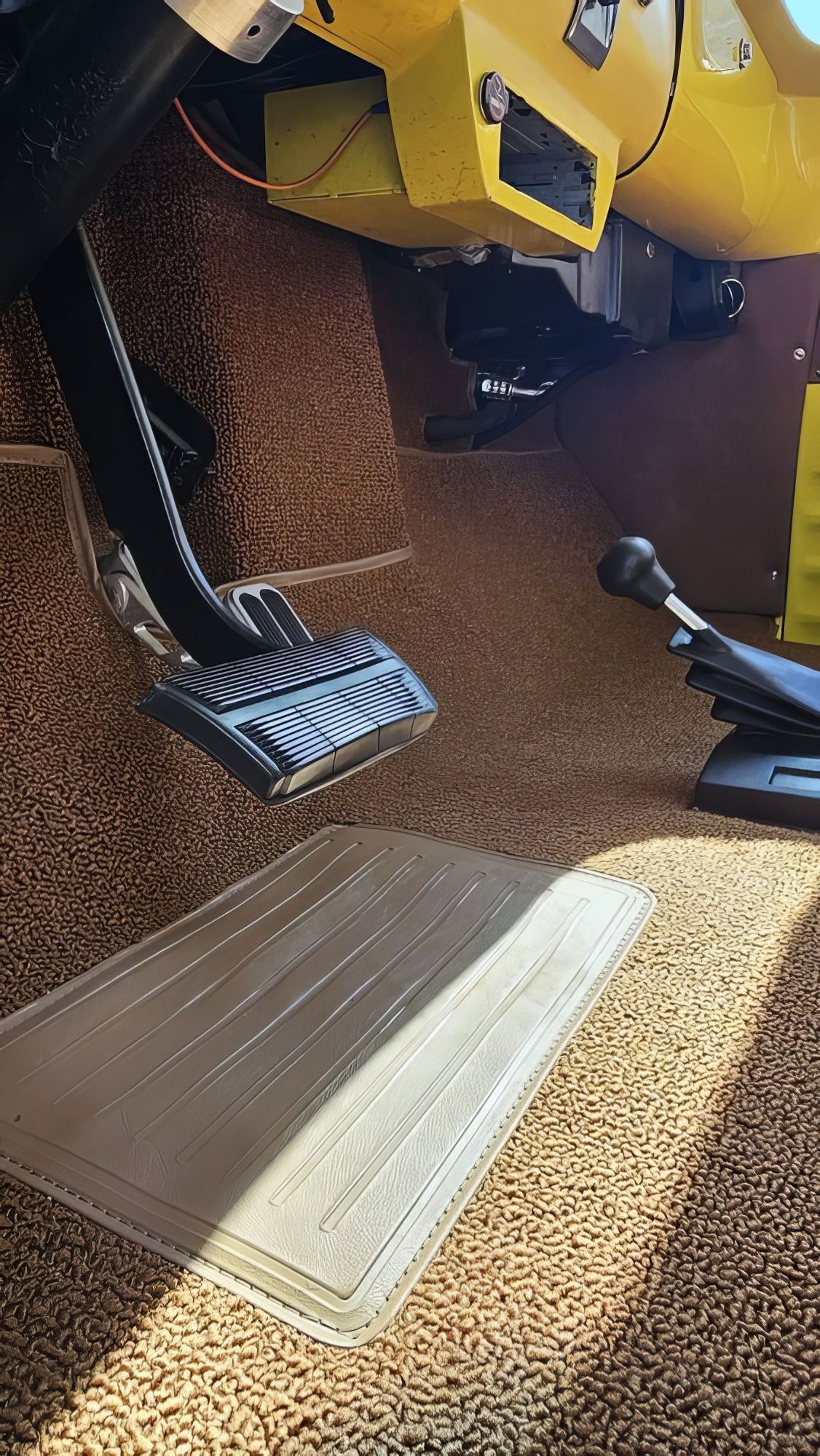 Yellow industrial machine close-up dumping wood chips onto a metal ramp and floor area.