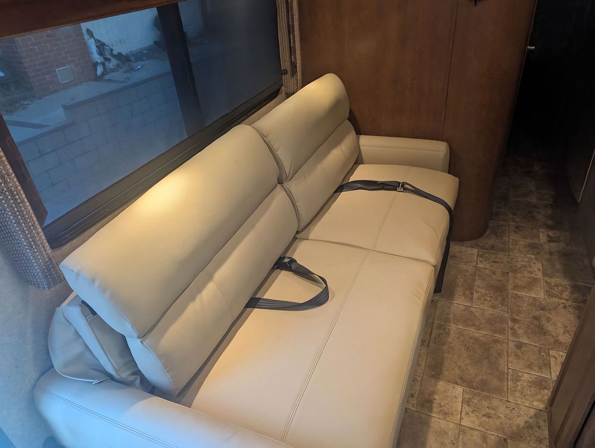 Light gray upholstered sofa with seat belts in a narrow wood-paneled room