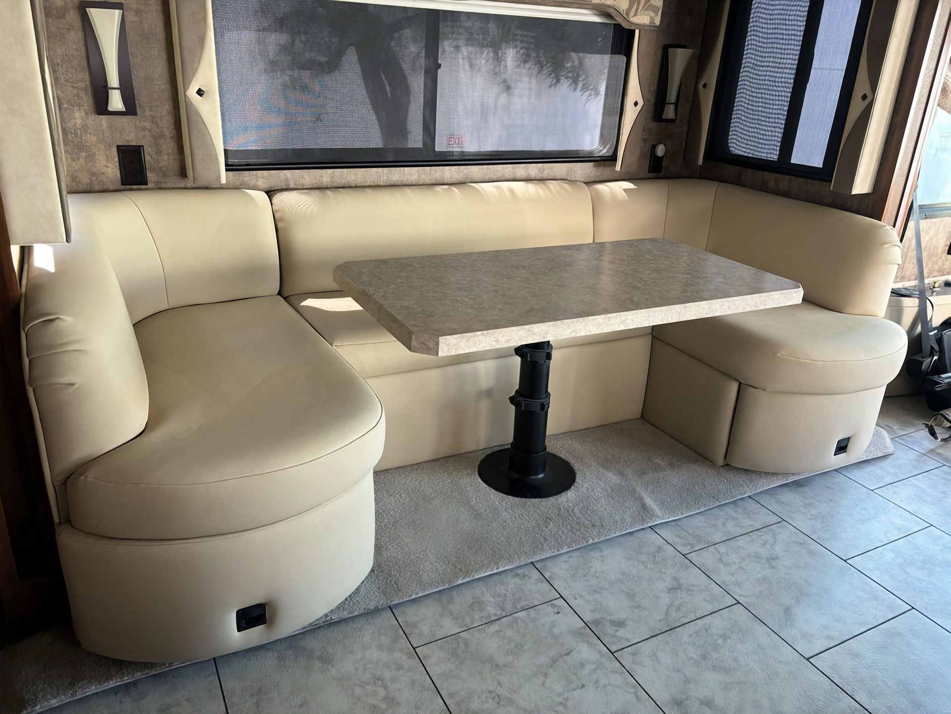 Beige U-shaped booth seating with a gray table in a tiled room.