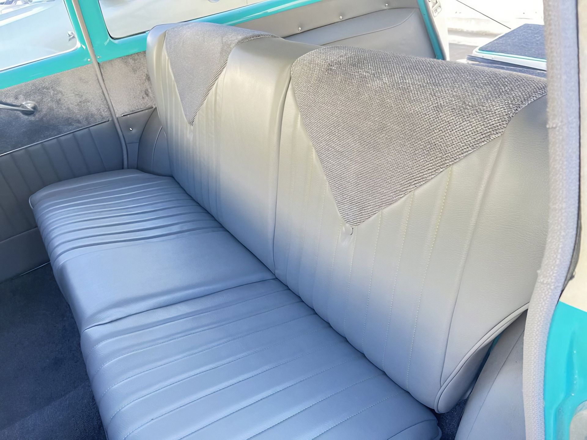 Blue-and-white vinyl bench seat inside a vintage car interior