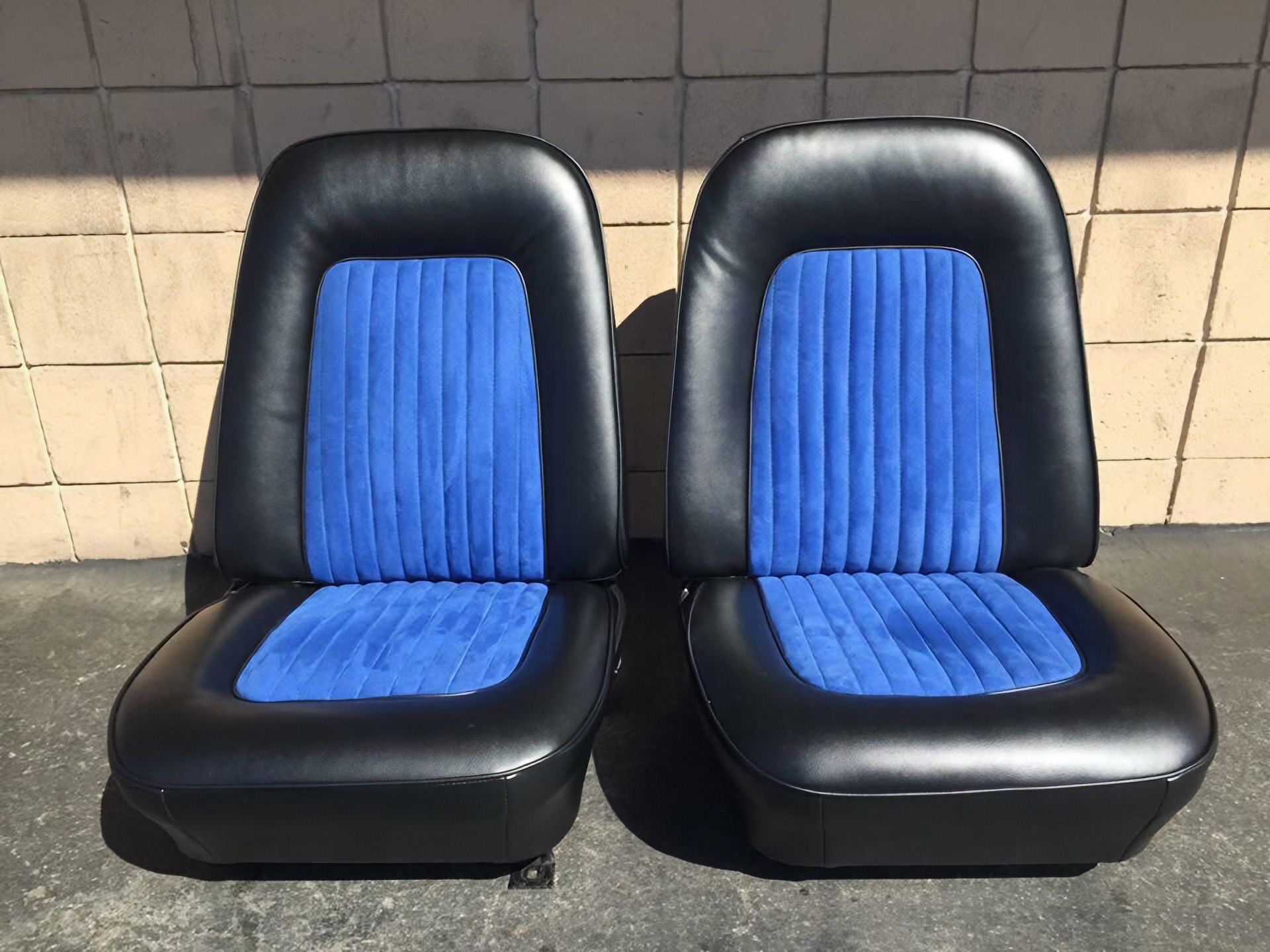 Two black and blue car seats side by side on a tiled floor