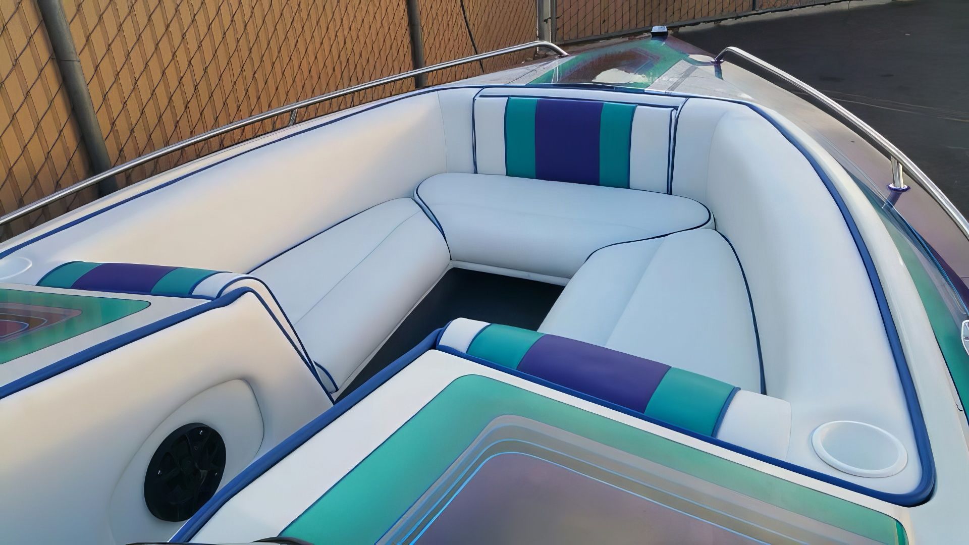 Inflatable boat interior with white, teal, and purple seating on a dockside setting