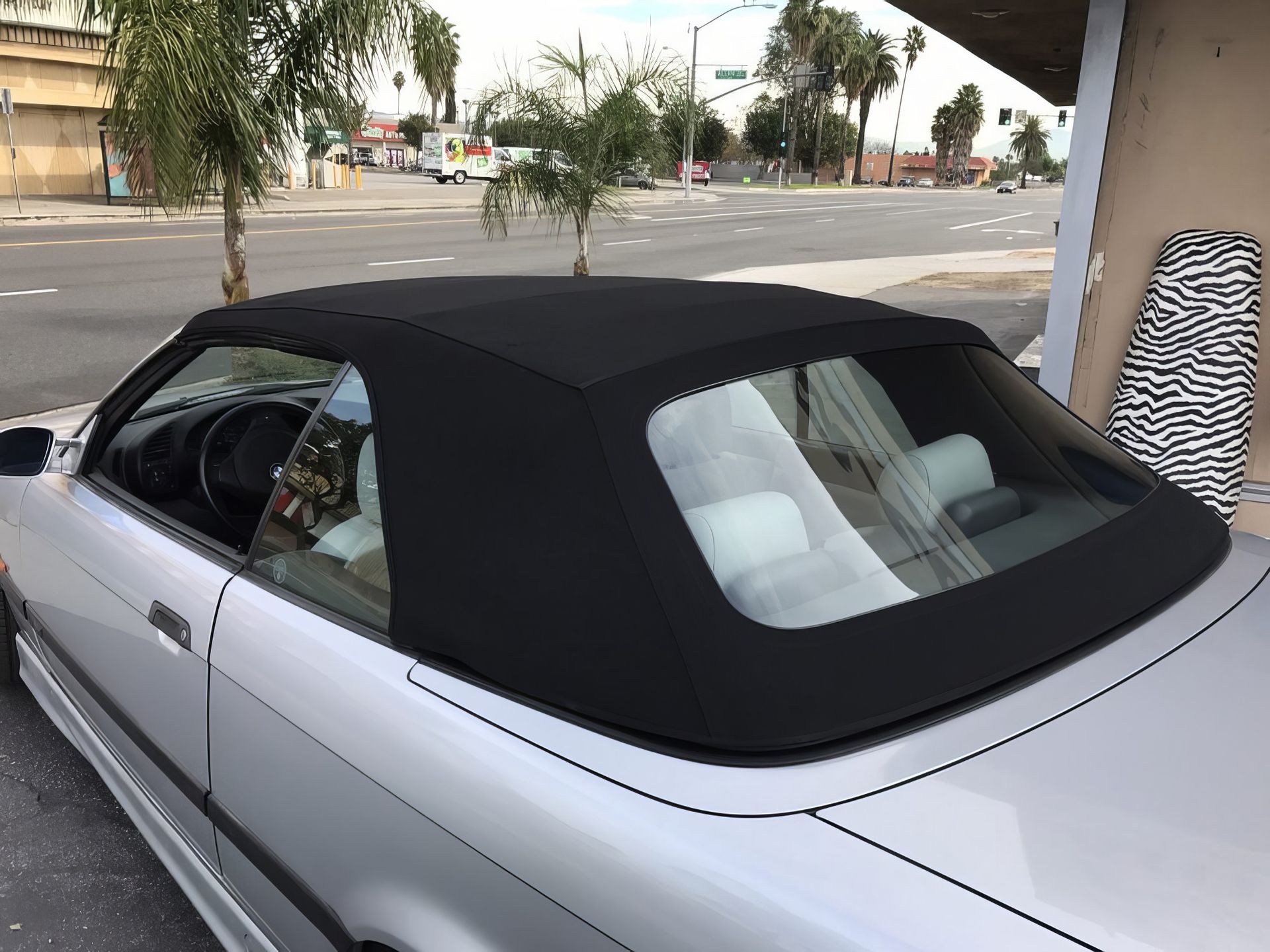 White convertible with black soft top parked on a street under a covered area