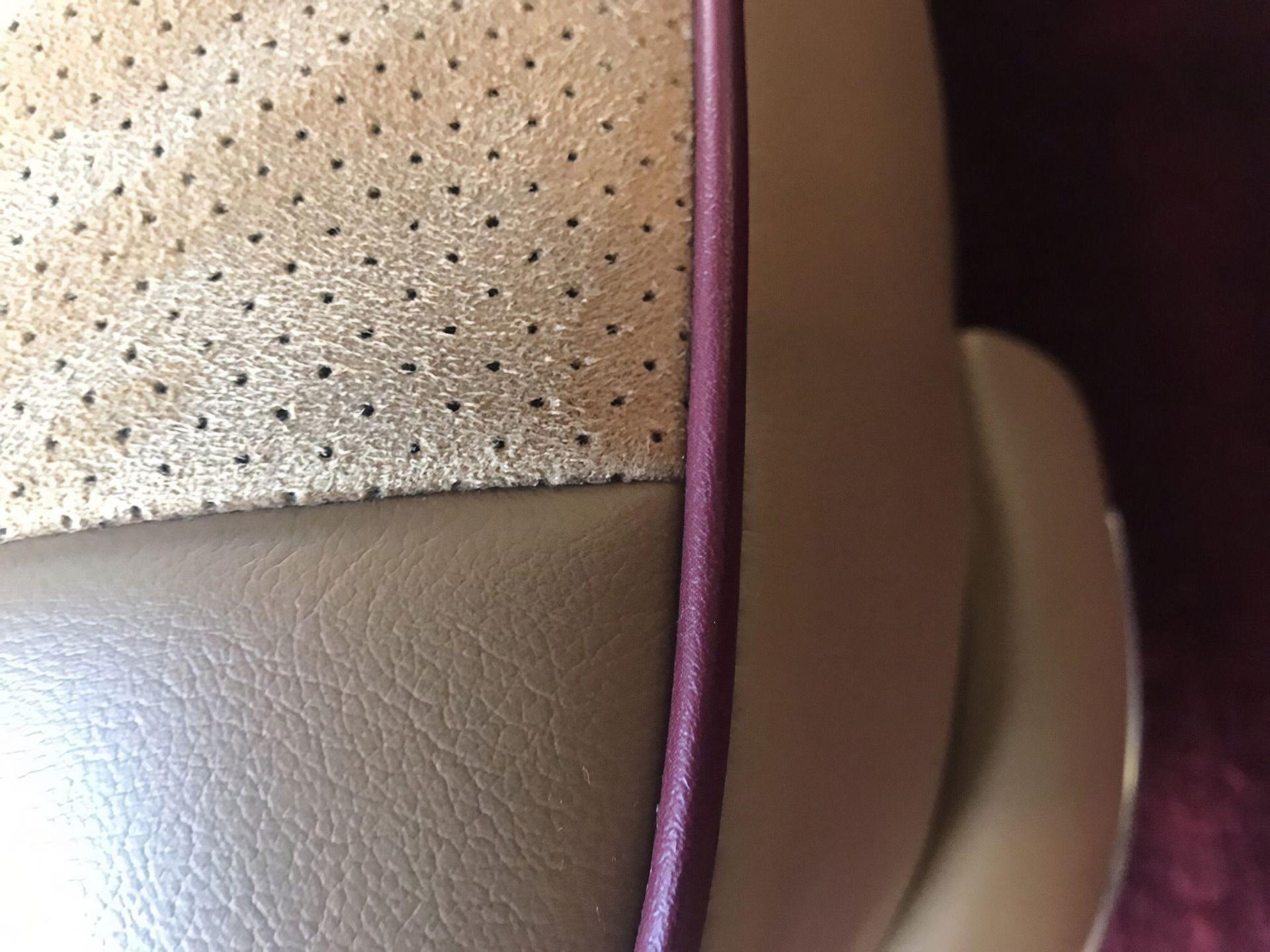 Close-up of a beige and brown car seat with a purple seam or trim
