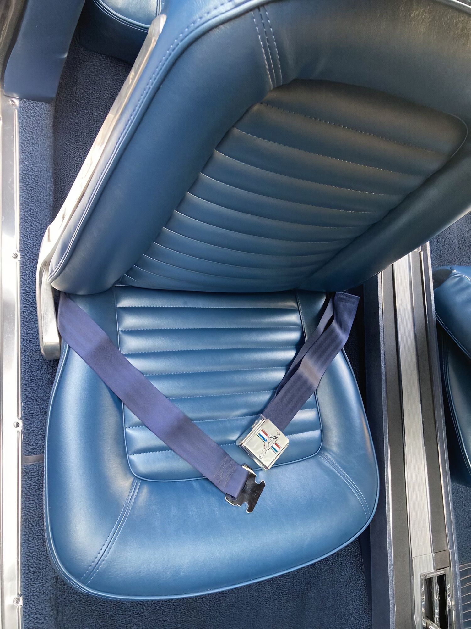 Blue car seat with a seatbelt fastened across it