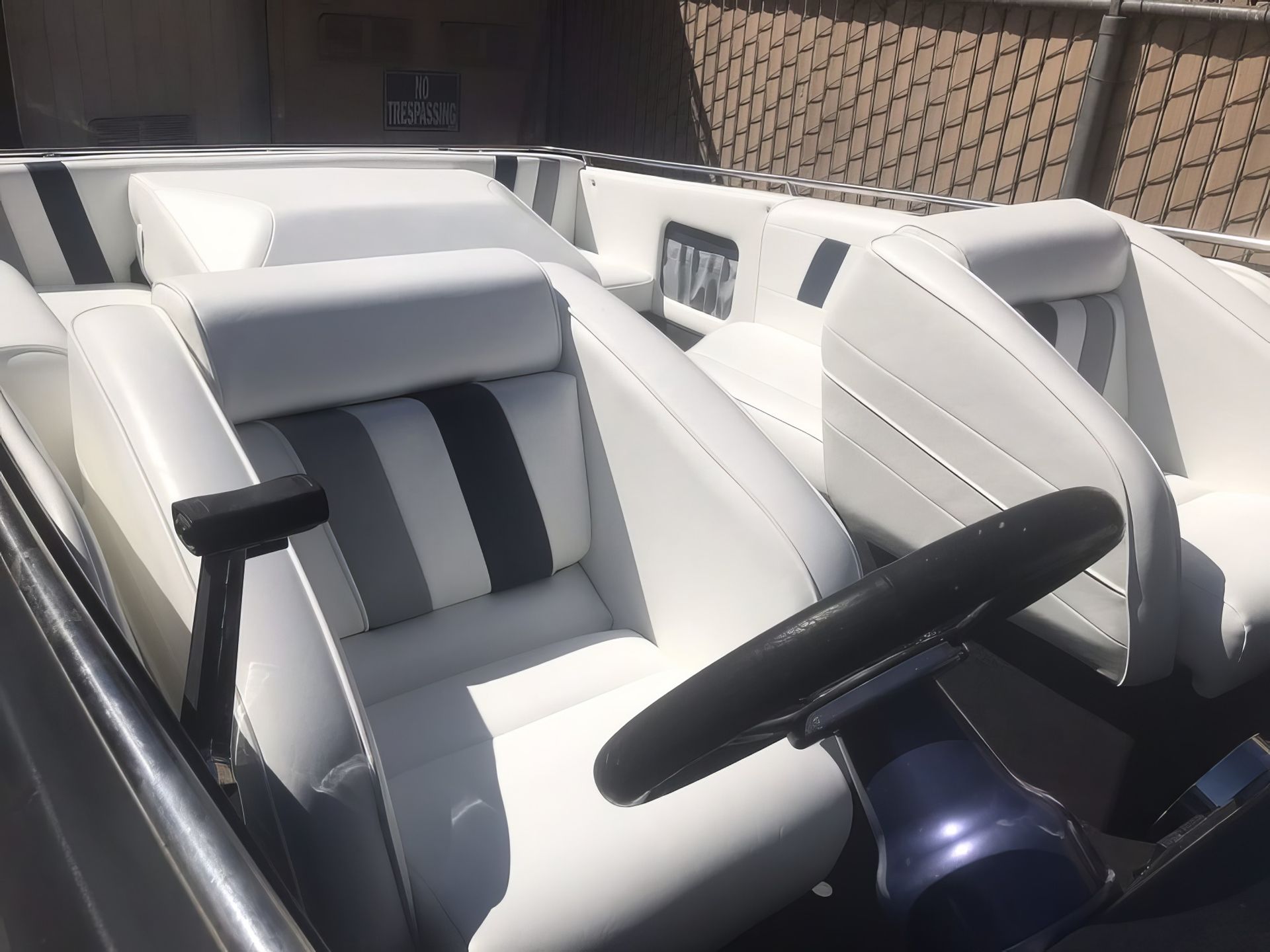 White and gray boat cockpit seats with black steering wheel under bright sunlight