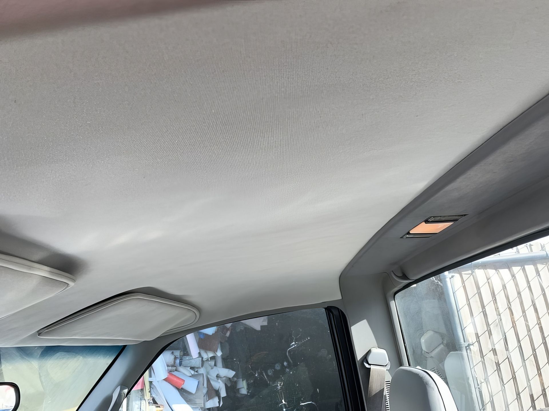 Interior of a car with light gray ceiling and side windows visible