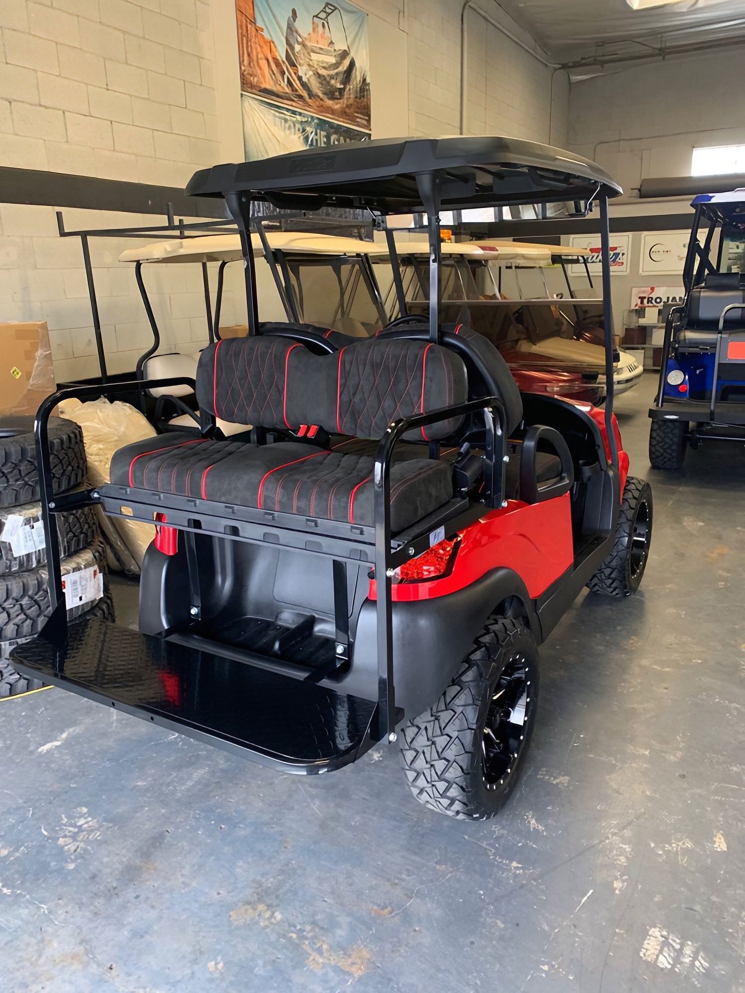 Red golf cart with black roof and seats parked inside a garage.