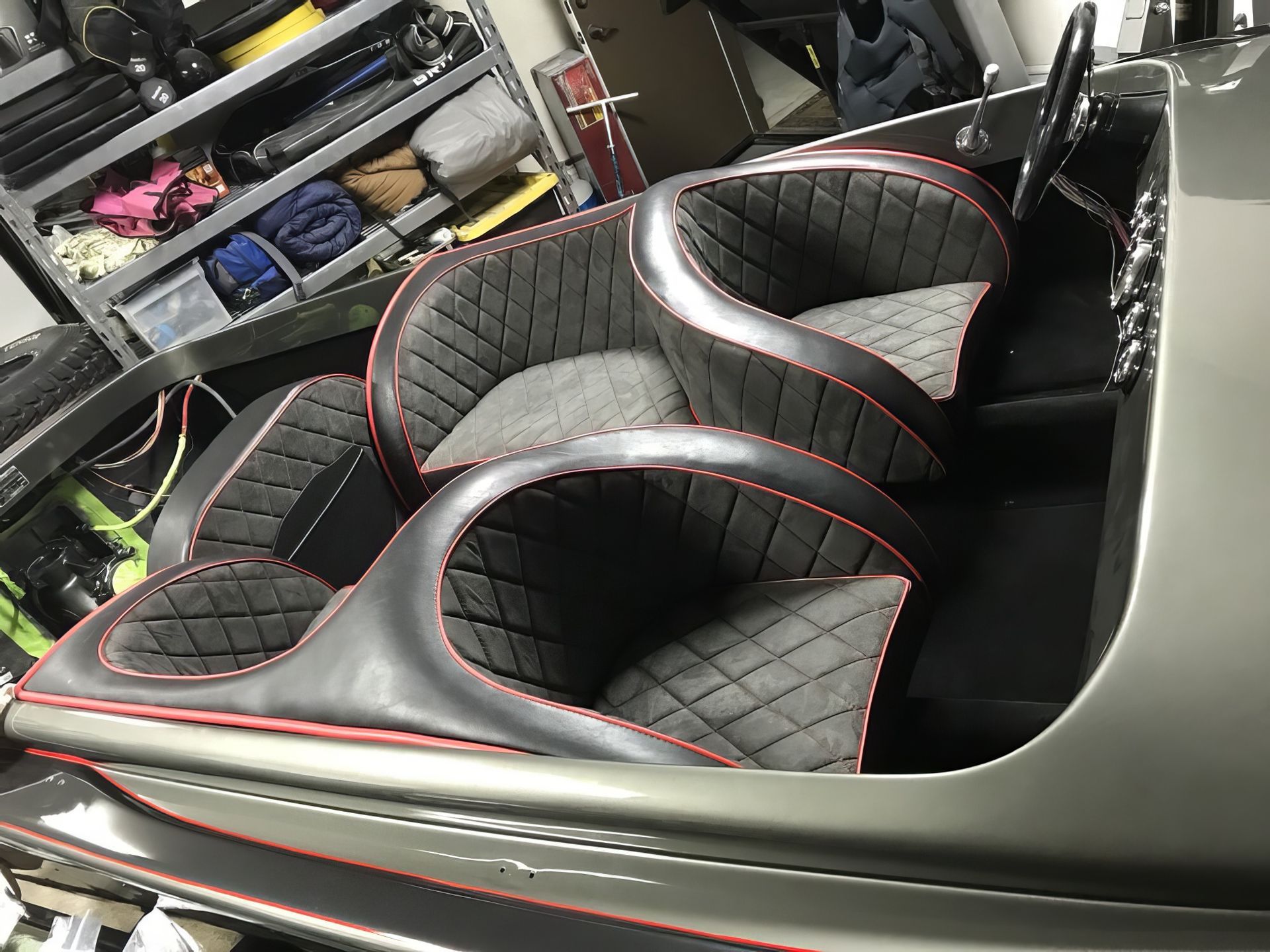 Custom black and red upholstered car seats in a workshop, shown from above.