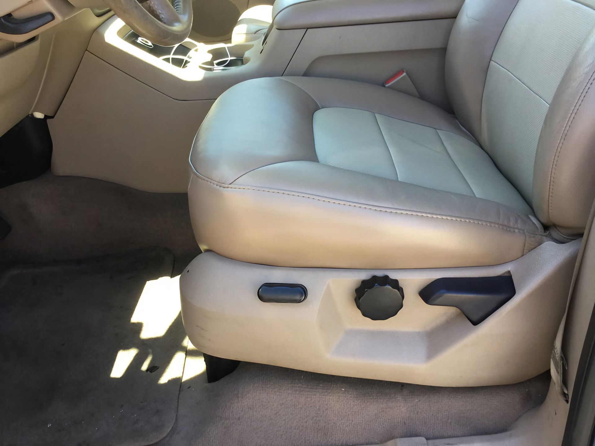 Beige car front seat with power adjustment controls and visible cup holder area