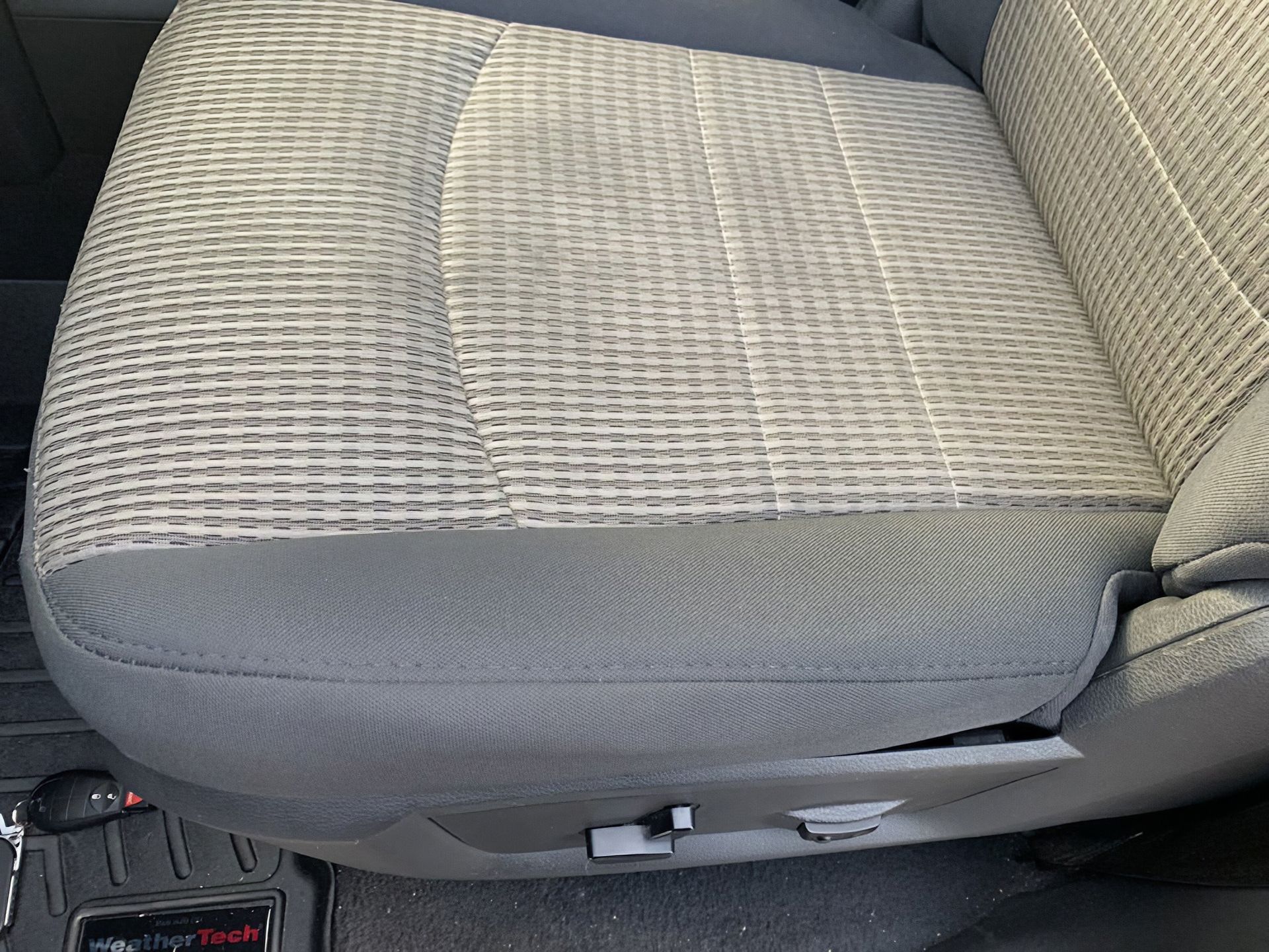 Gray cloth car seat cushion with patterned center panel and adjustment controls visible at the base