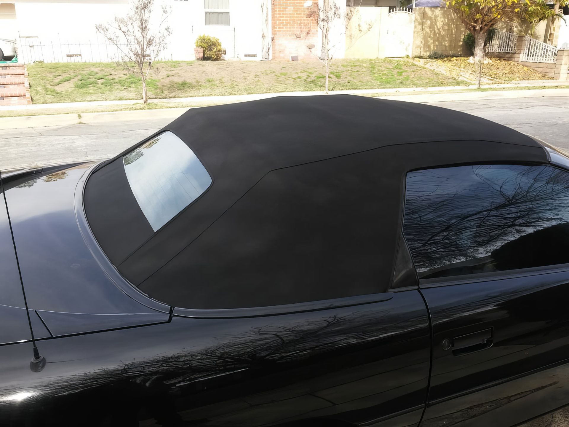 Black convertible with a raised soft top parked on a residential street.